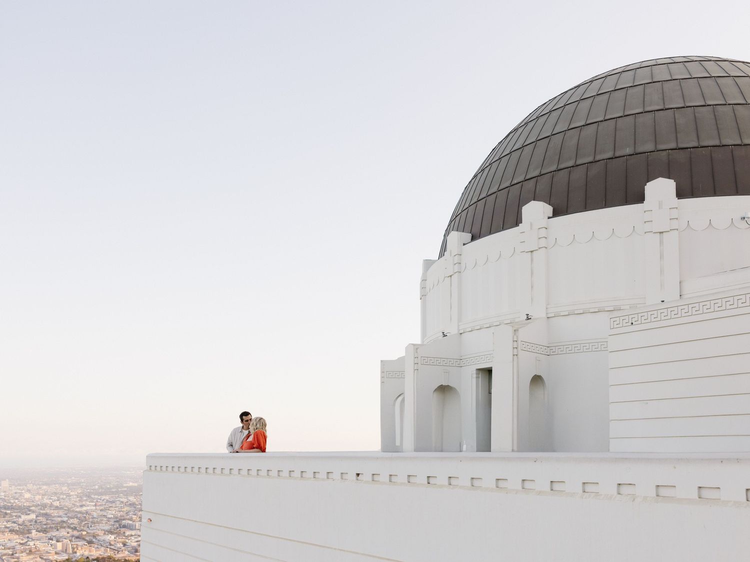 Iconic white domed buildings of Griffith Observatory against a bright sky in Los Angeles.