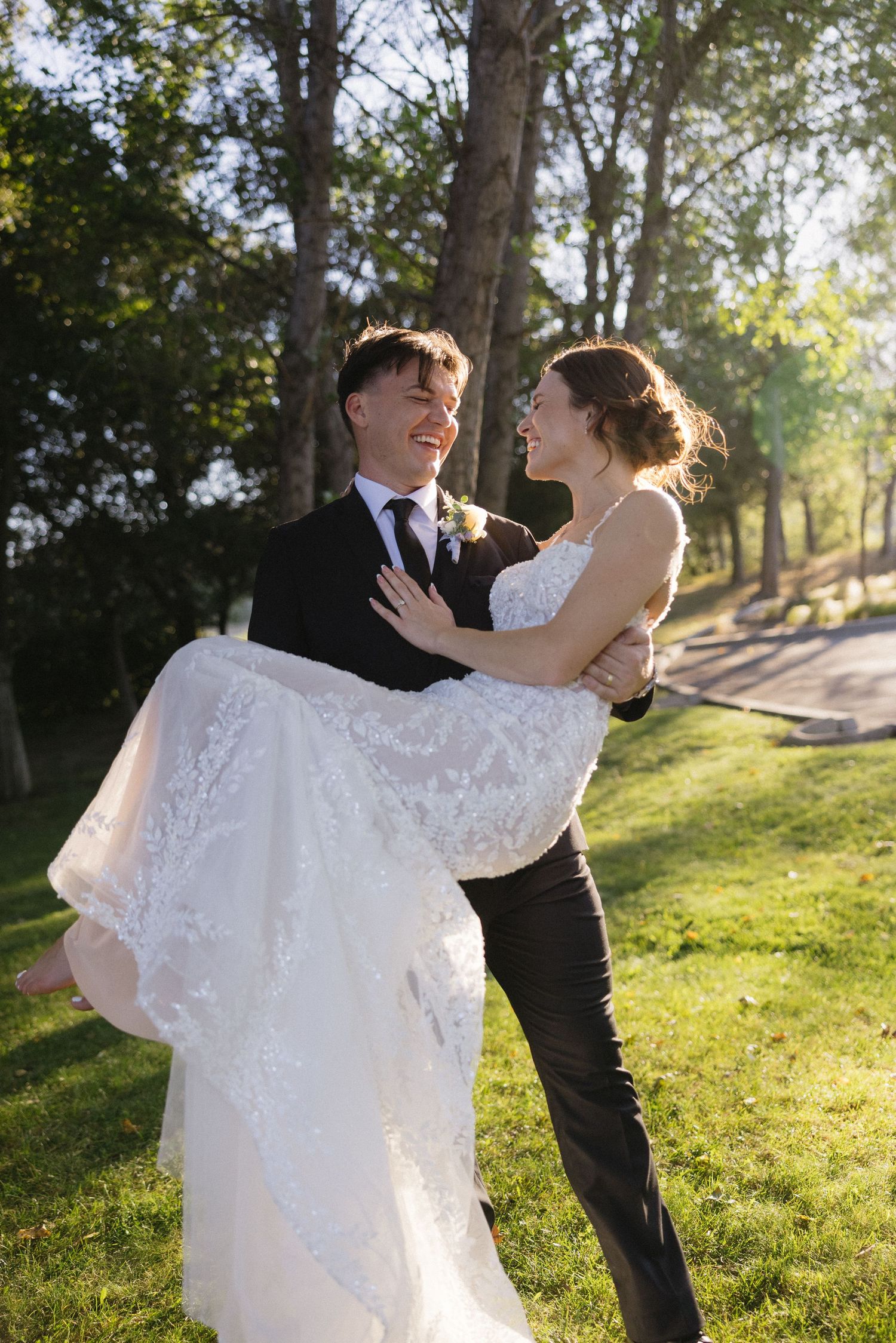 Joyful wedding couple dancing and twirling on sunny hillside with trees.