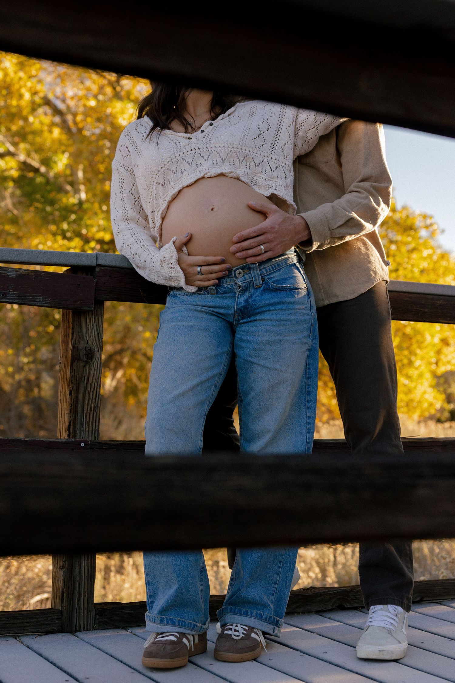 Intimate close-up shot of couple in casual wear on wooden deck during sunset.