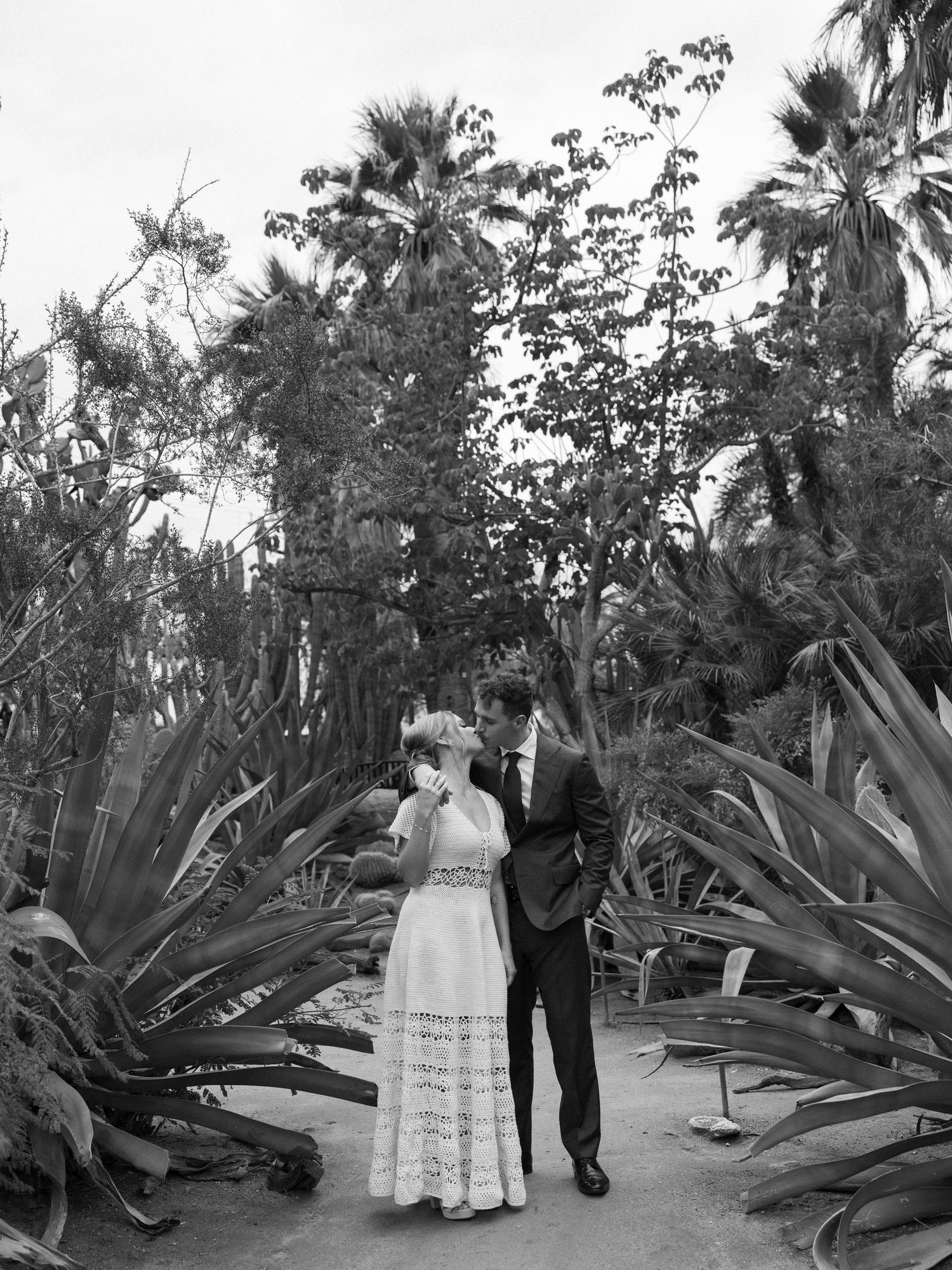 Romantic garden photoshoot among large tropical plants and palm trees in black and white.