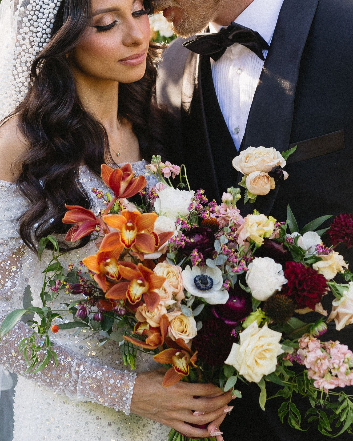 Close-up of vibrant autumn wedding bouquet with orange orchids and deep burgundy blooms.