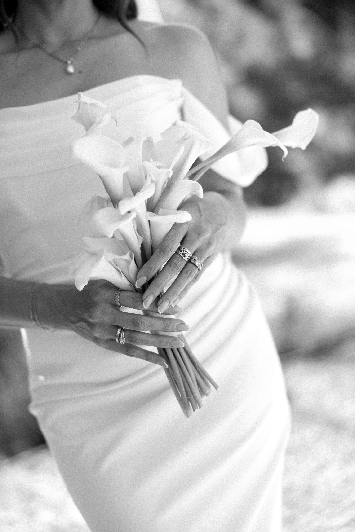 Bride in white strapless gown holding elegant calla lily bouquet, black and white wedding photo.