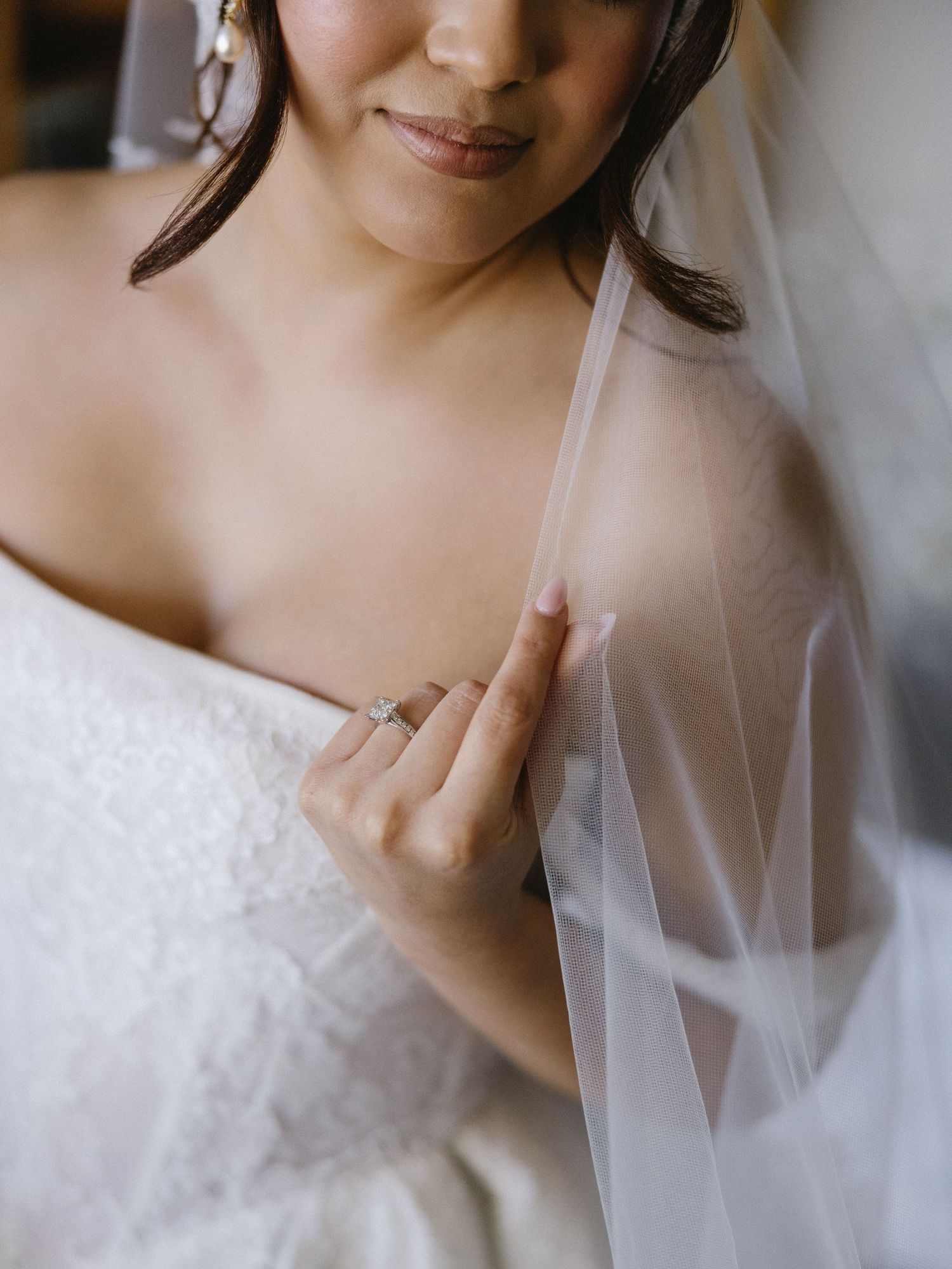 Close-up details of delicate white wedding veil and dress fabric in soft lighting.