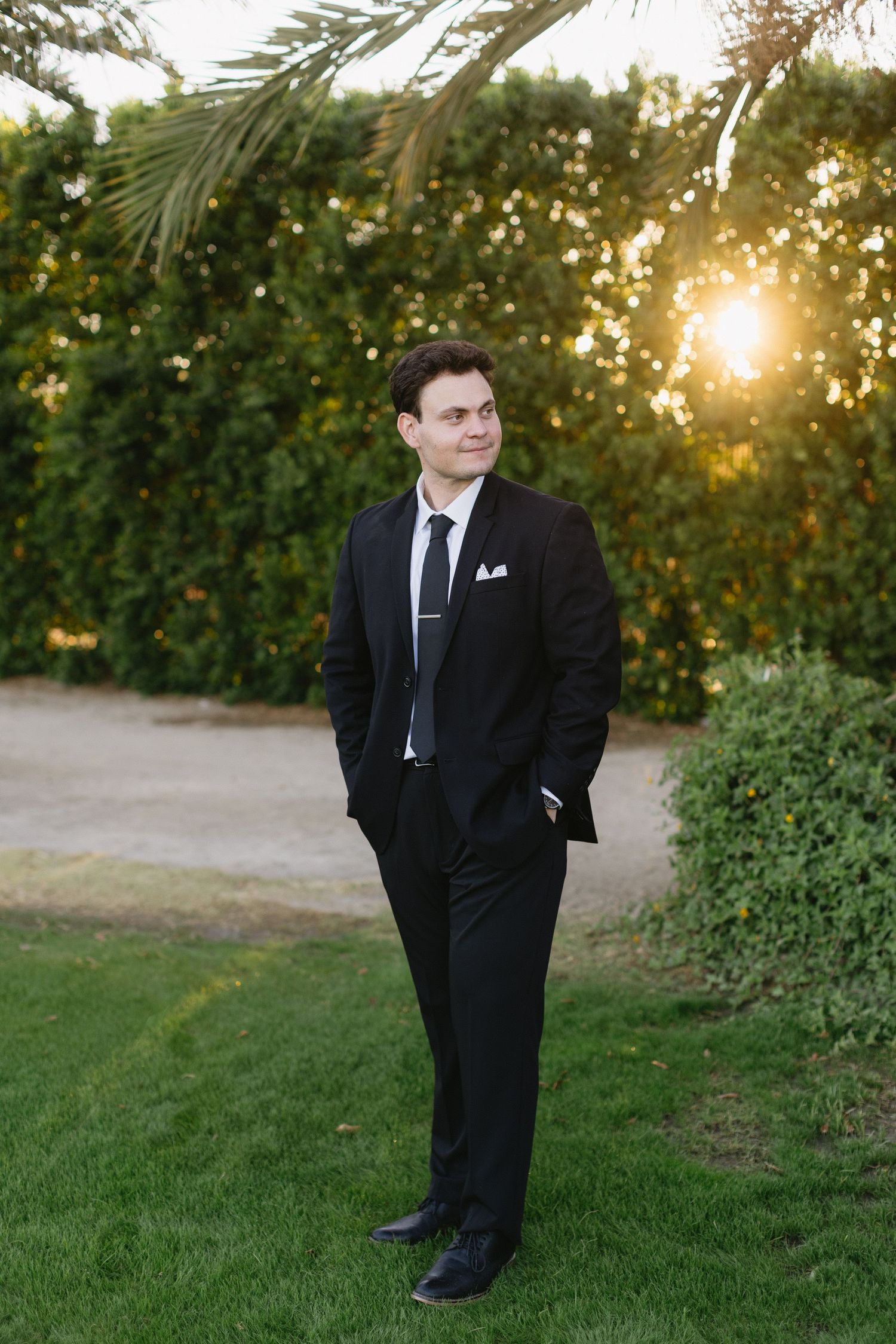 Formal attire against a natural outdoor setting with golden sunlight filtering through trees.