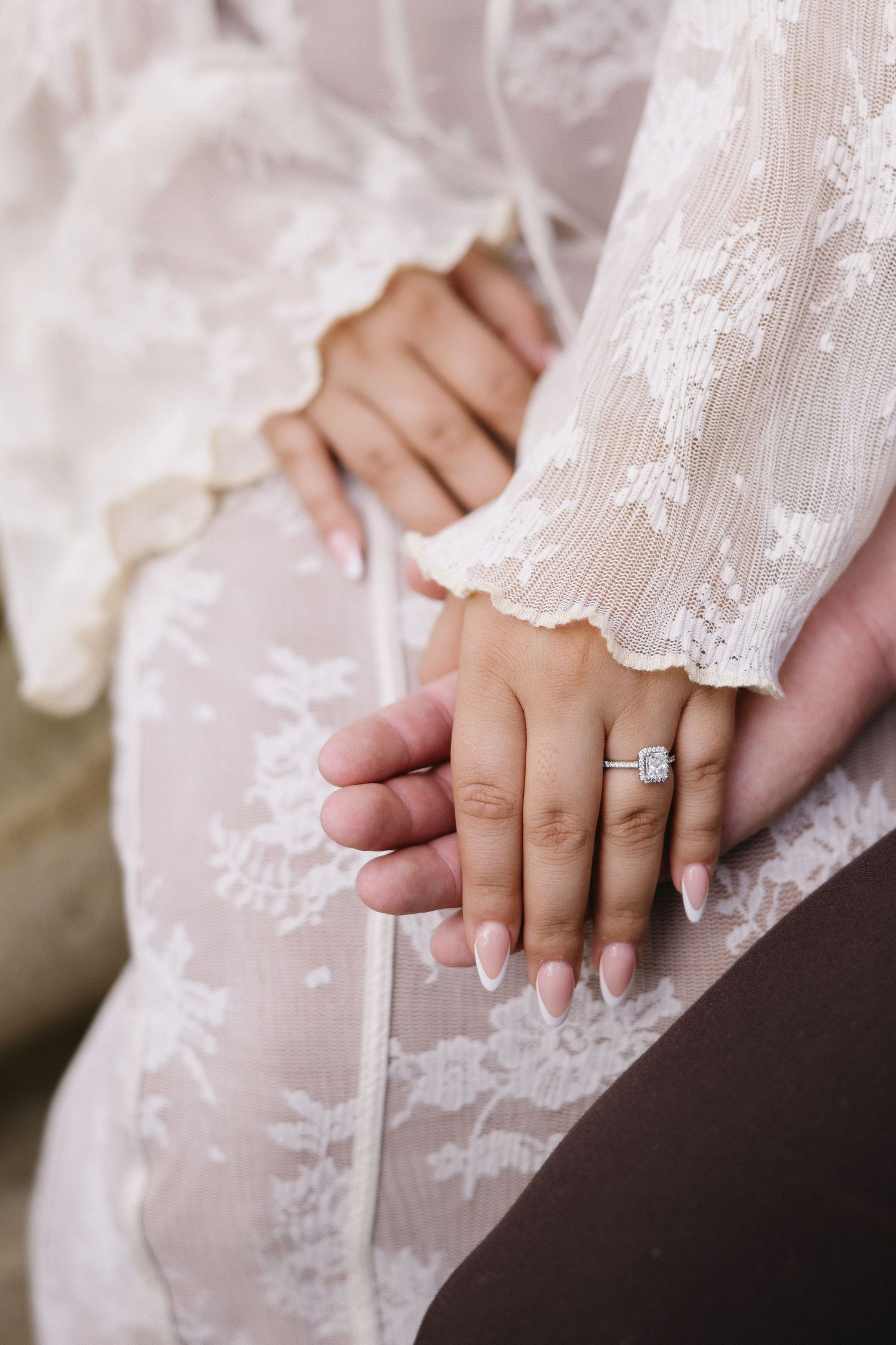 Close-up shots of hands with an engagement ring on delicate lace fabric.