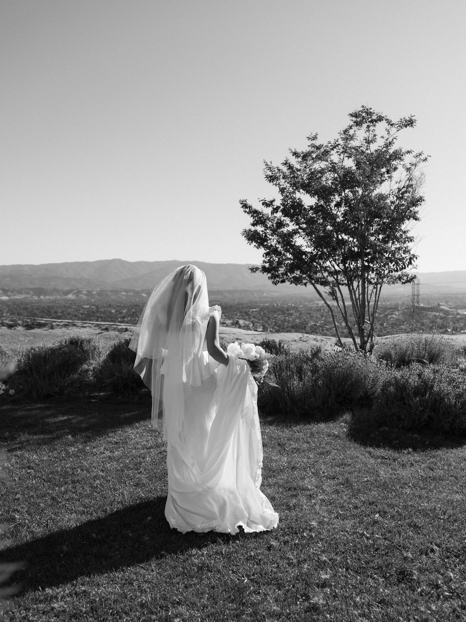 Artistic black and white photos of a figure in flowing white fabric moving across a hilltop landscape.