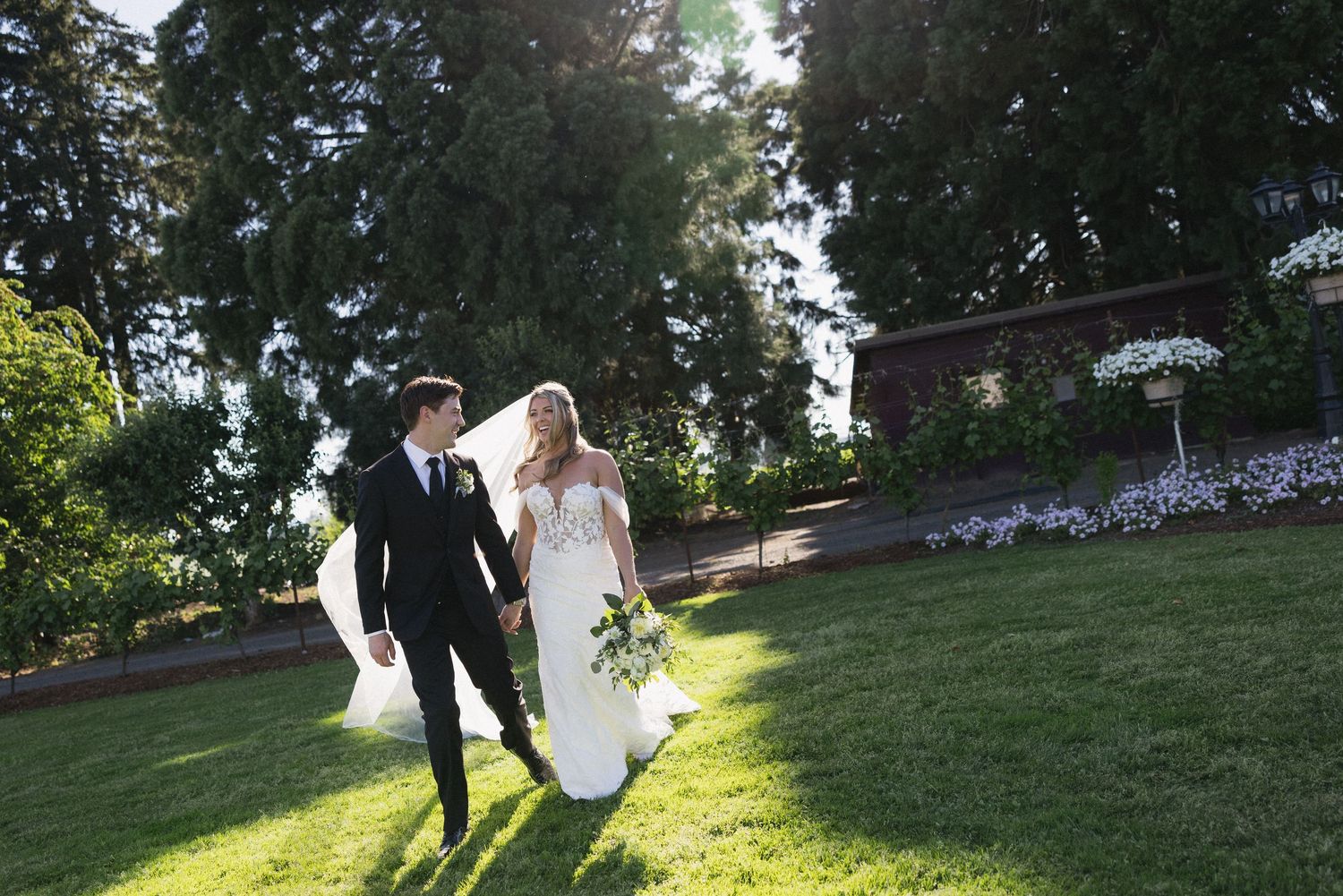 Couple walking through a sunlit garden path during golden hour.