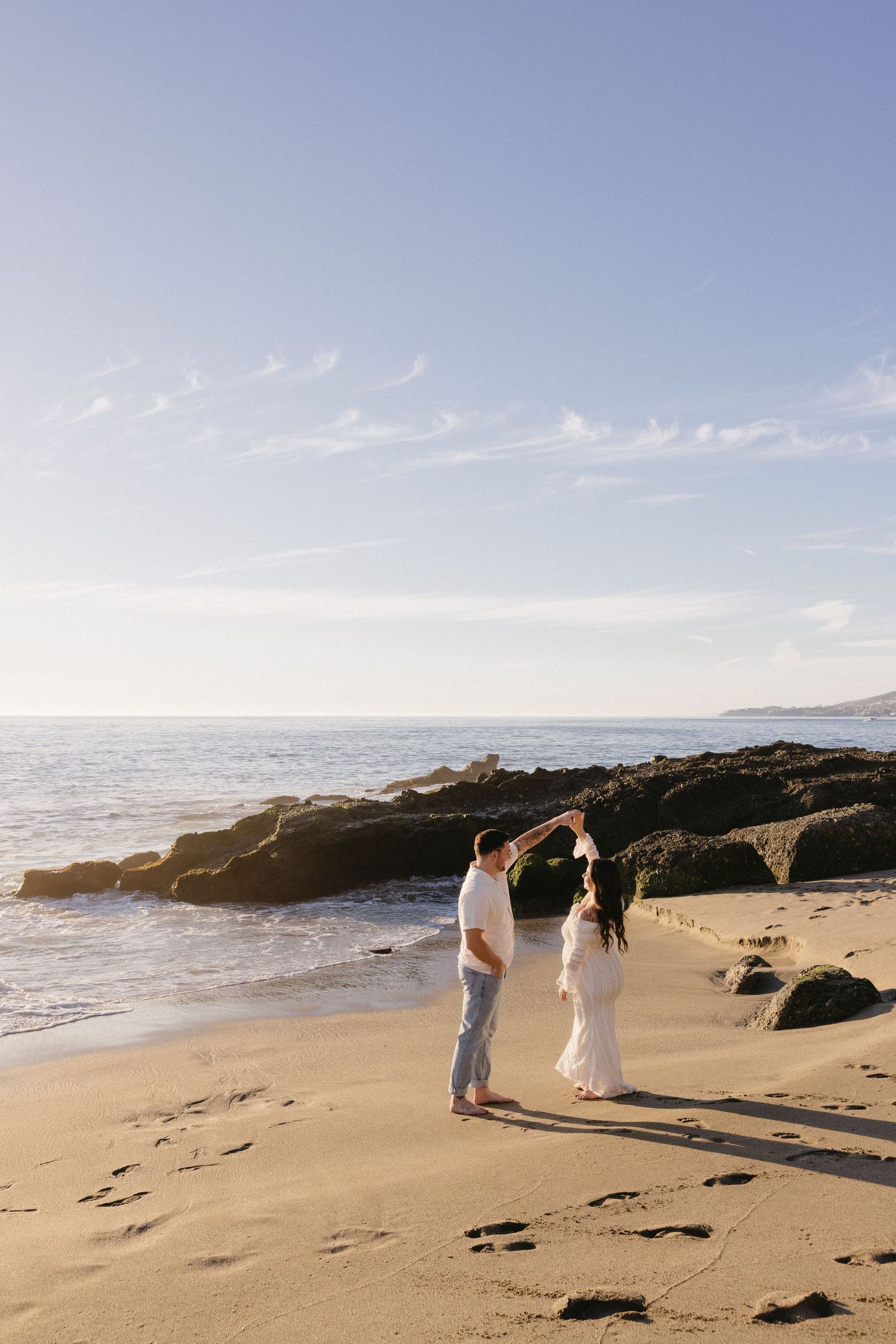 Romantic beach ceremony among rocky coastline during golden hour.