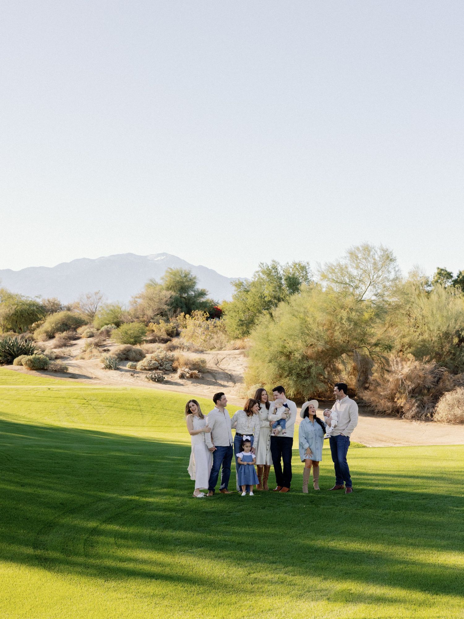 Family group photo session on a sunny golf course with desert landscape.