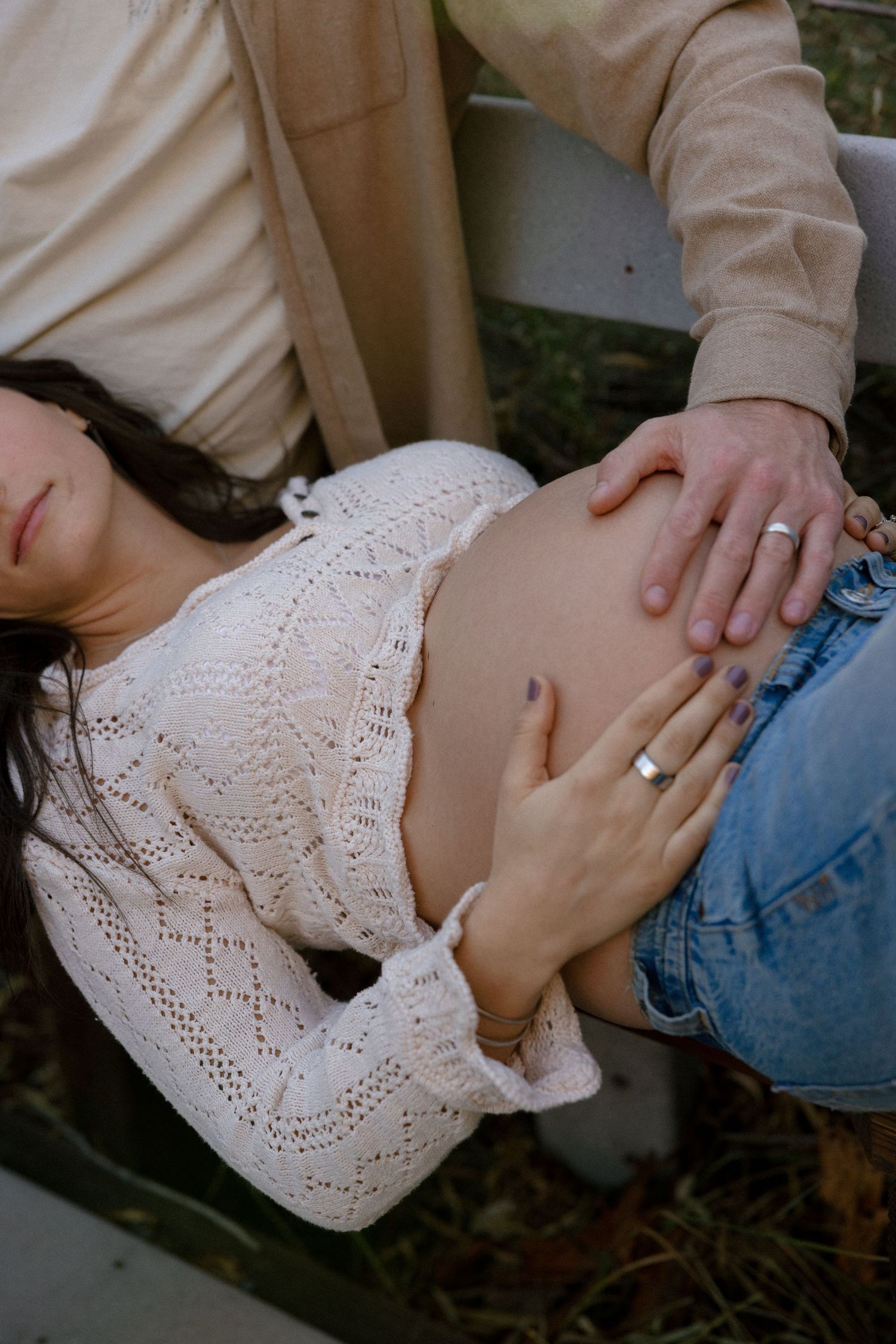 Close-up of hands embracing in white lace and denim clothing.