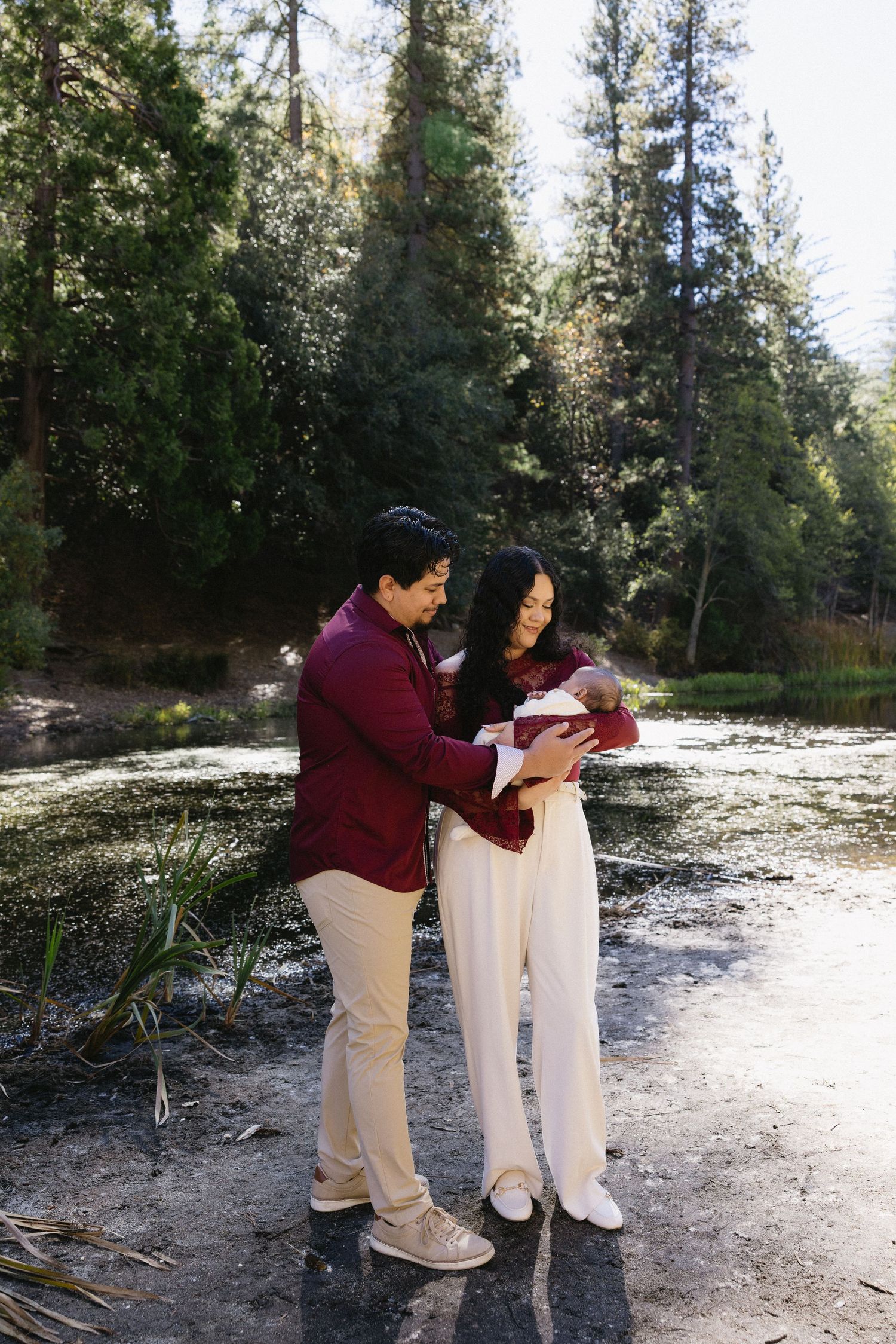 Family photography session on rocky lakeshore with pine forest background.