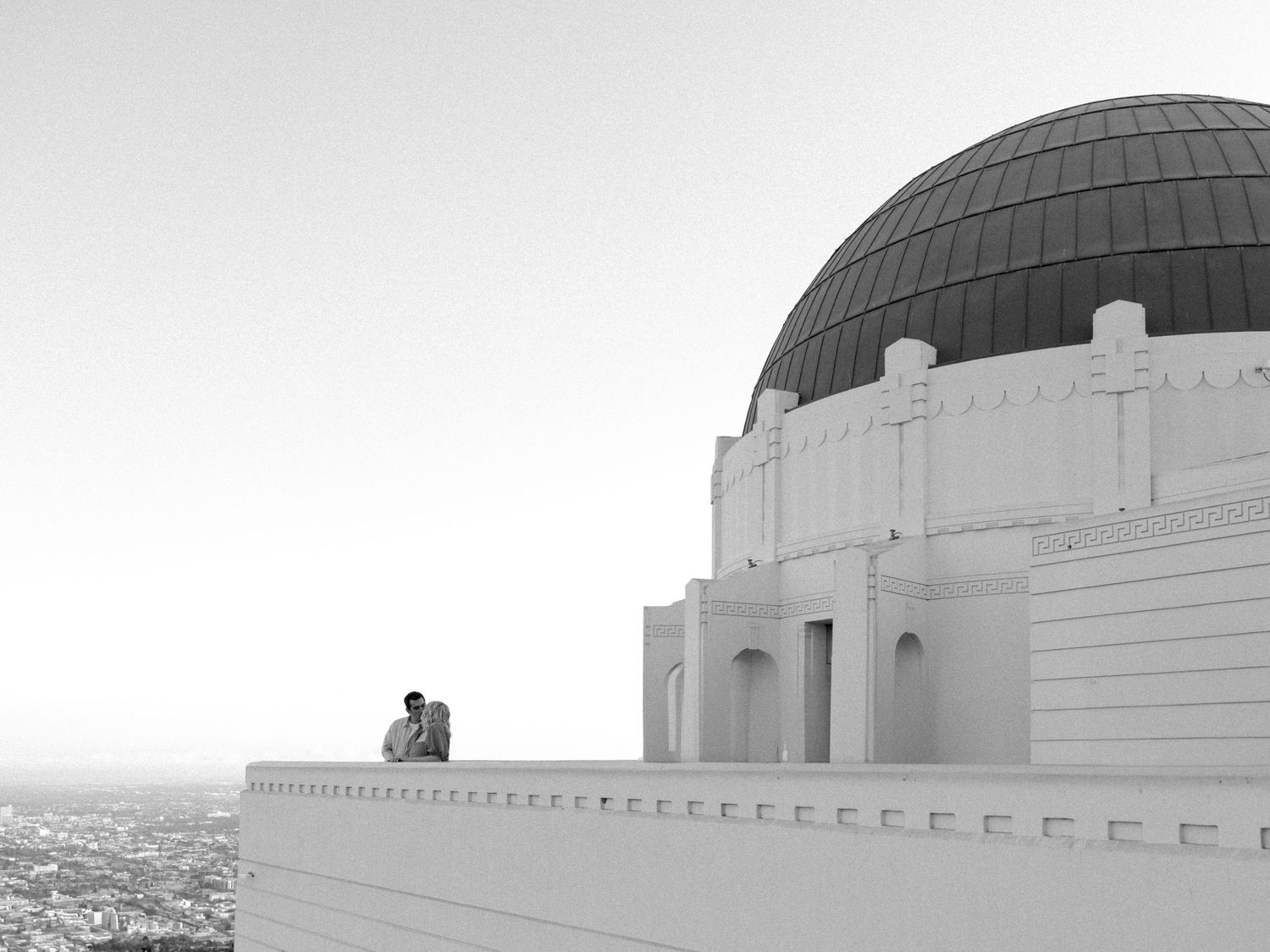 View of the iconic Griffith Observatory domes against a bright sky in Los Angeles.