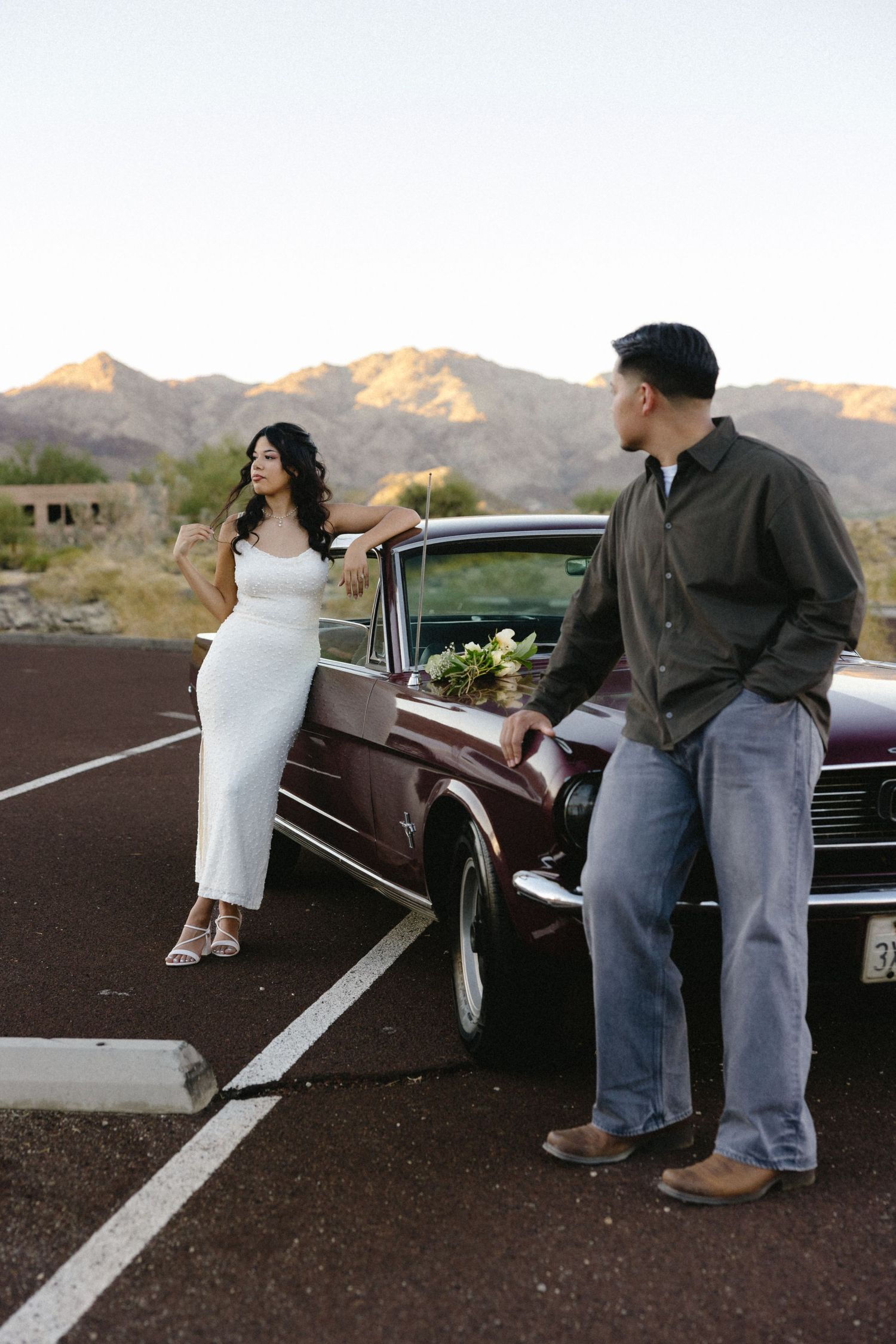 Engagement photos with classic car against desert mountain backdrop.