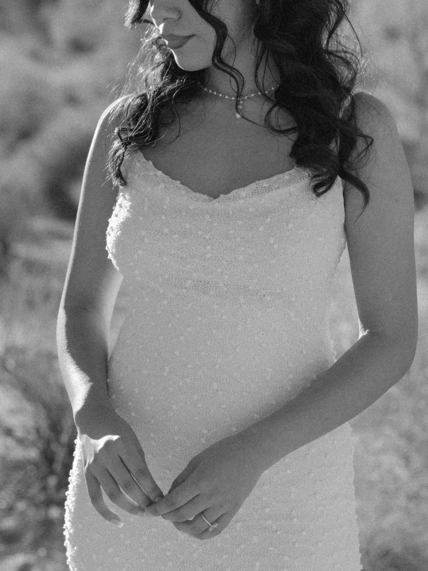 Close-up portrait of bride in white lace dress outdoors.