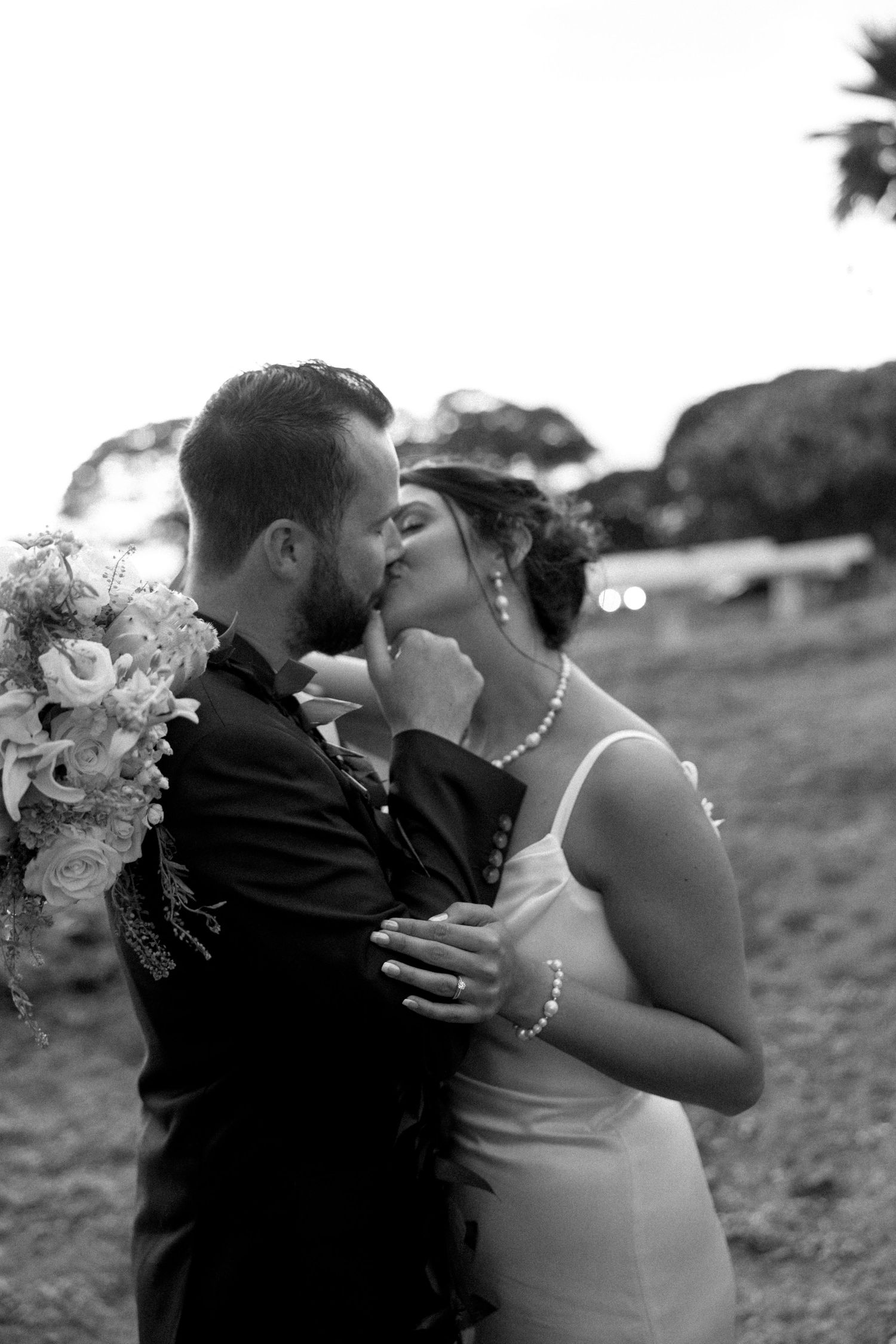 Black and white romantic wedding portrait of a couple sharing an intimate kiss.