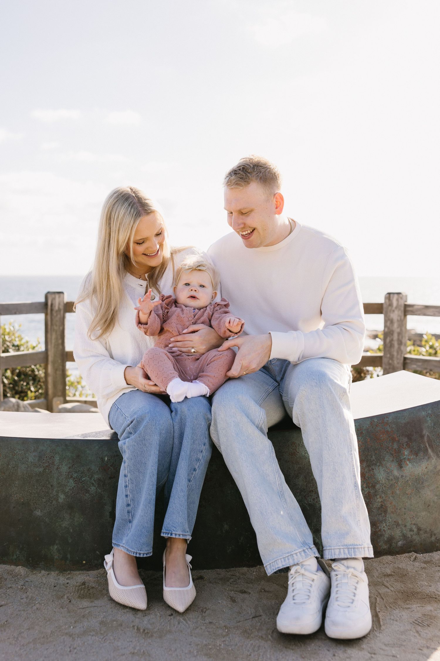 Family sitting together on bench sharing joyful moment in casual attire.