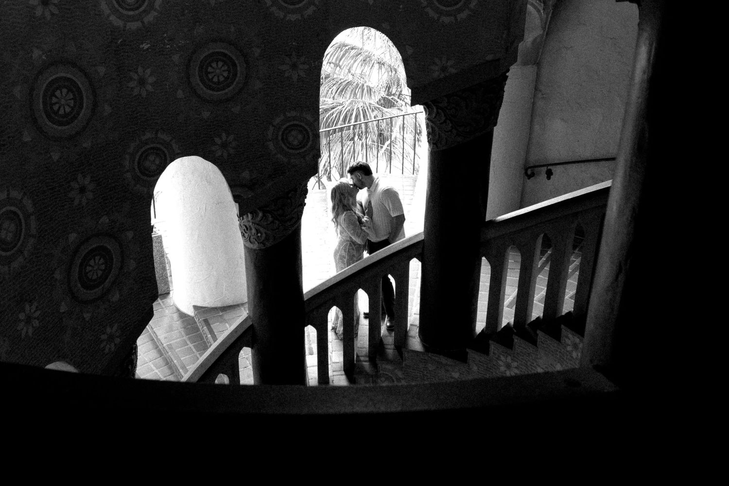 Dark silhouettes against bright archways in a Spanish colonial building.