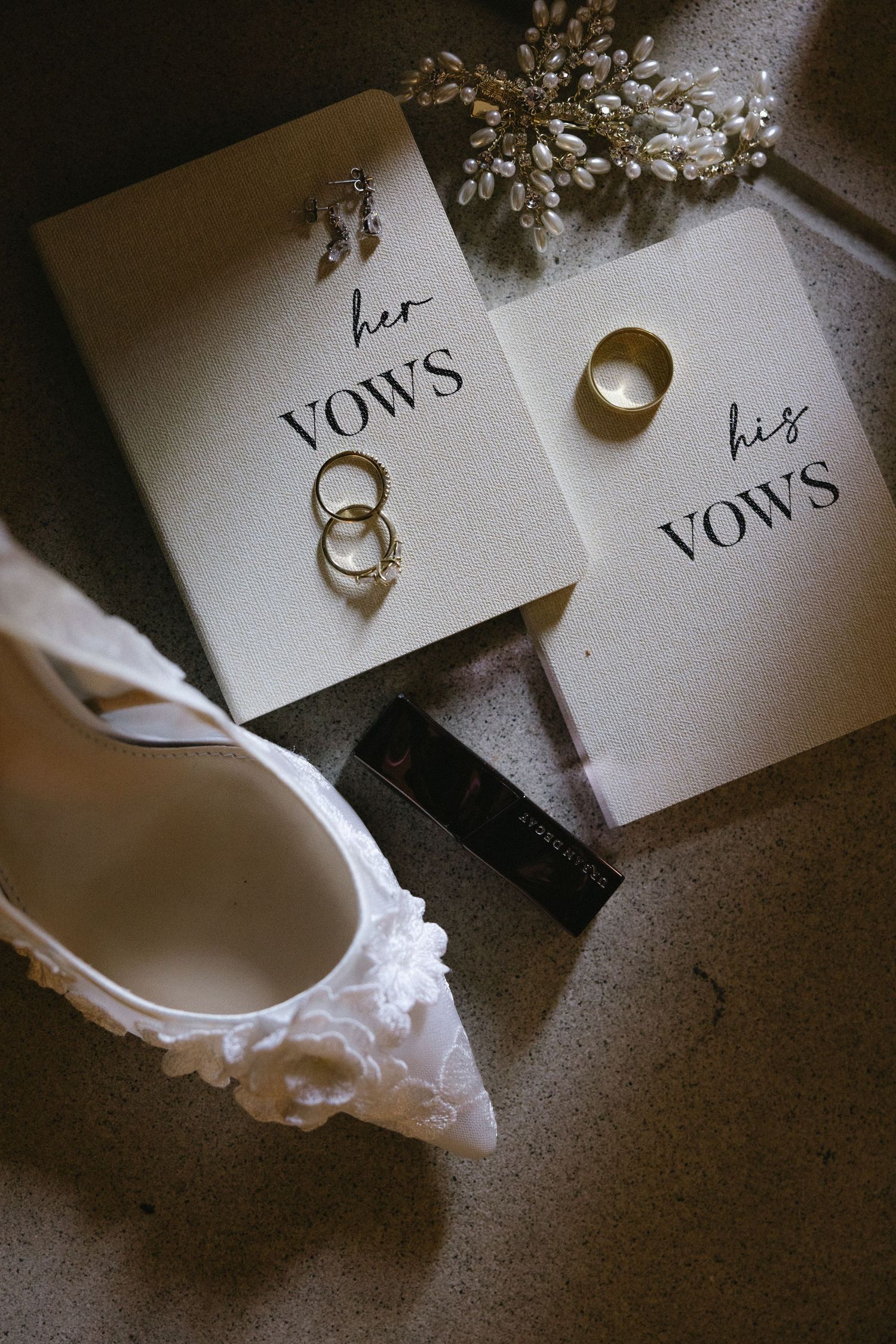 Wedding vows cards and rings arranged with white floral accessories.