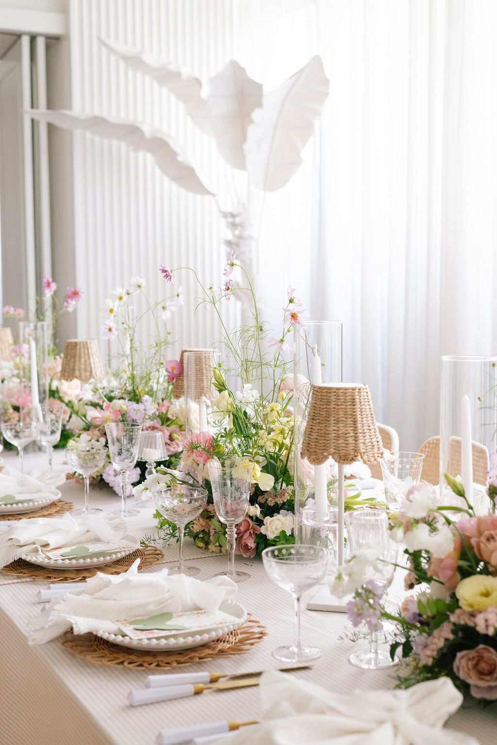 Bright white dining room with elegant table settings and pink floral centerpieces.