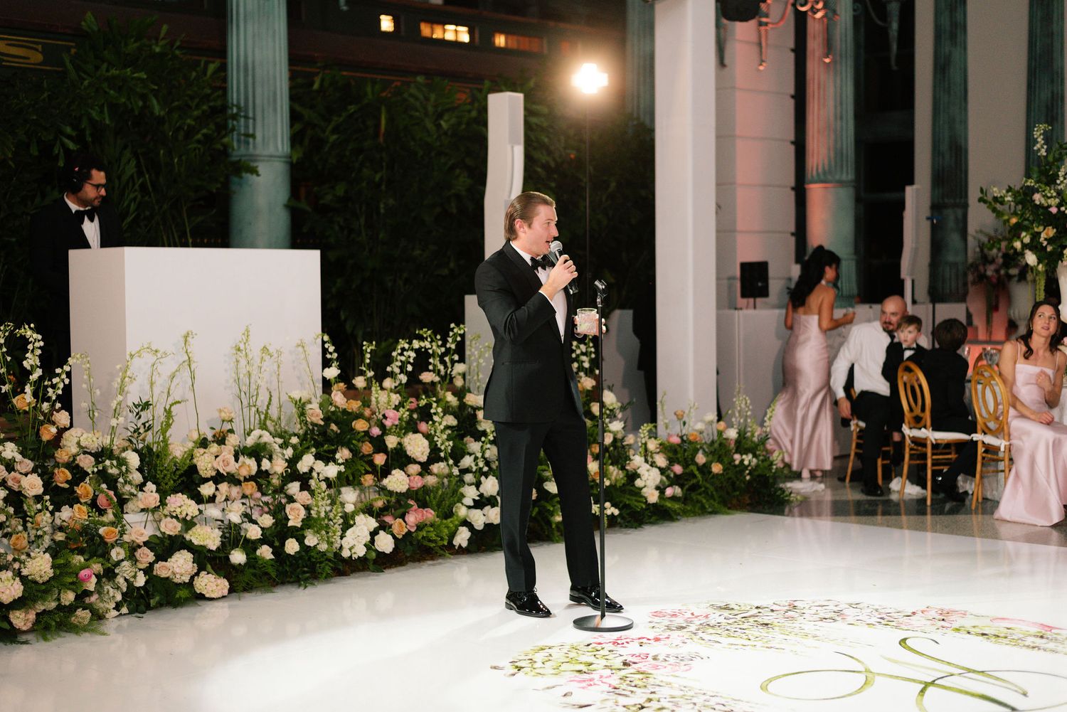 Wedding venue decorated with elegant white floral arrangements and ambient lighting.