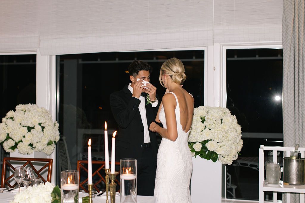 Couple shares emotional moment during candlelit wedding reception dinner.