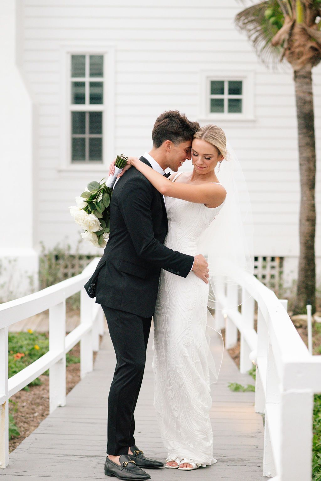 Intimate wedding couple moments captured on white porch walkway.