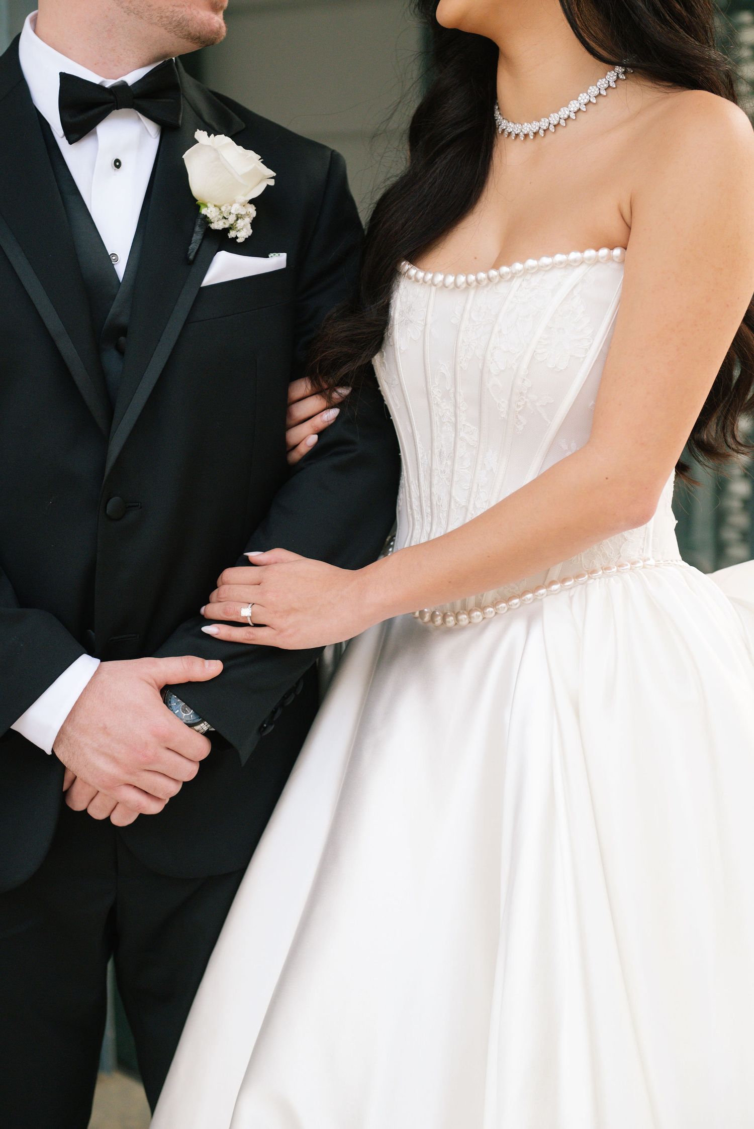 Elegant wedding details featuring a white strapless gown and classic black tuxedo.