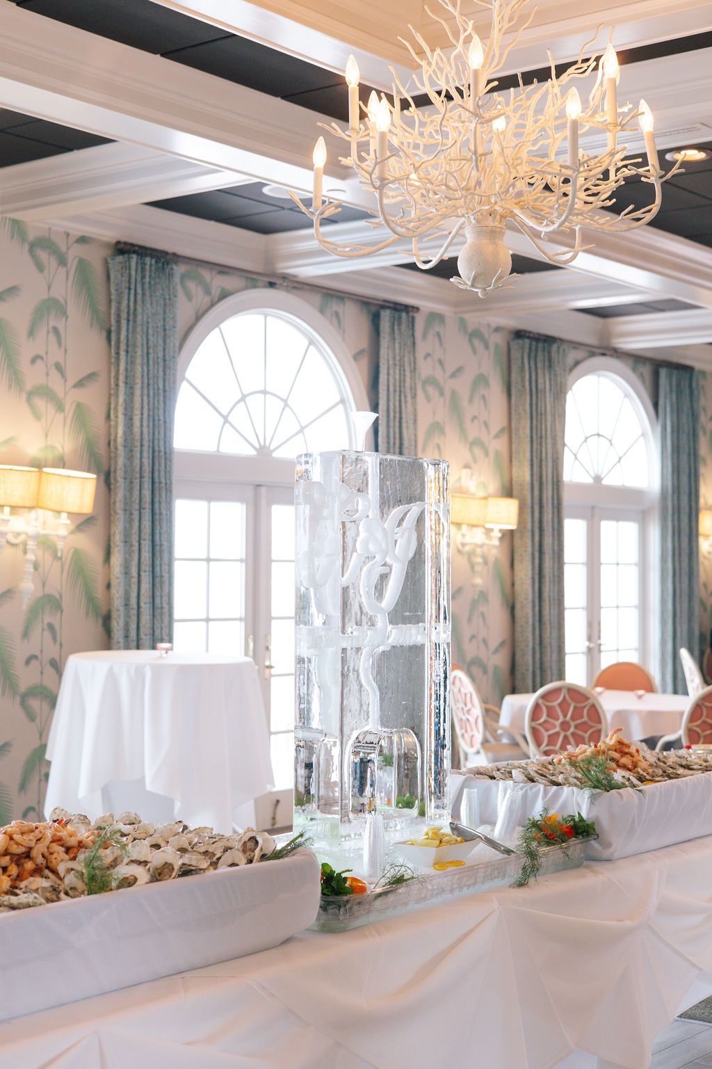 Luxurious dining room with crystal chandeliers and a long buffet table set against mint green wallpaper.