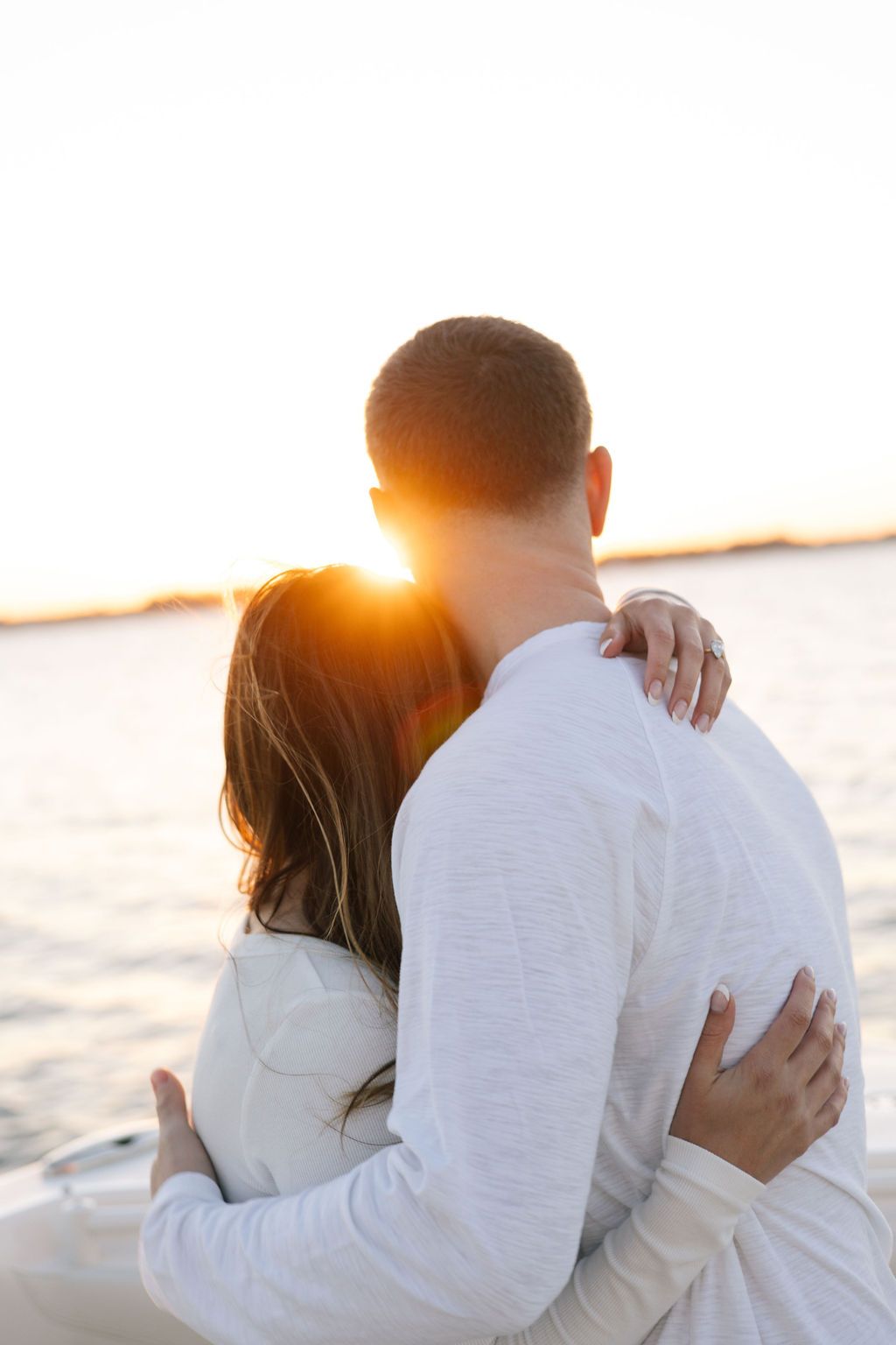 Intimate embrace on boat deck during golden hour.