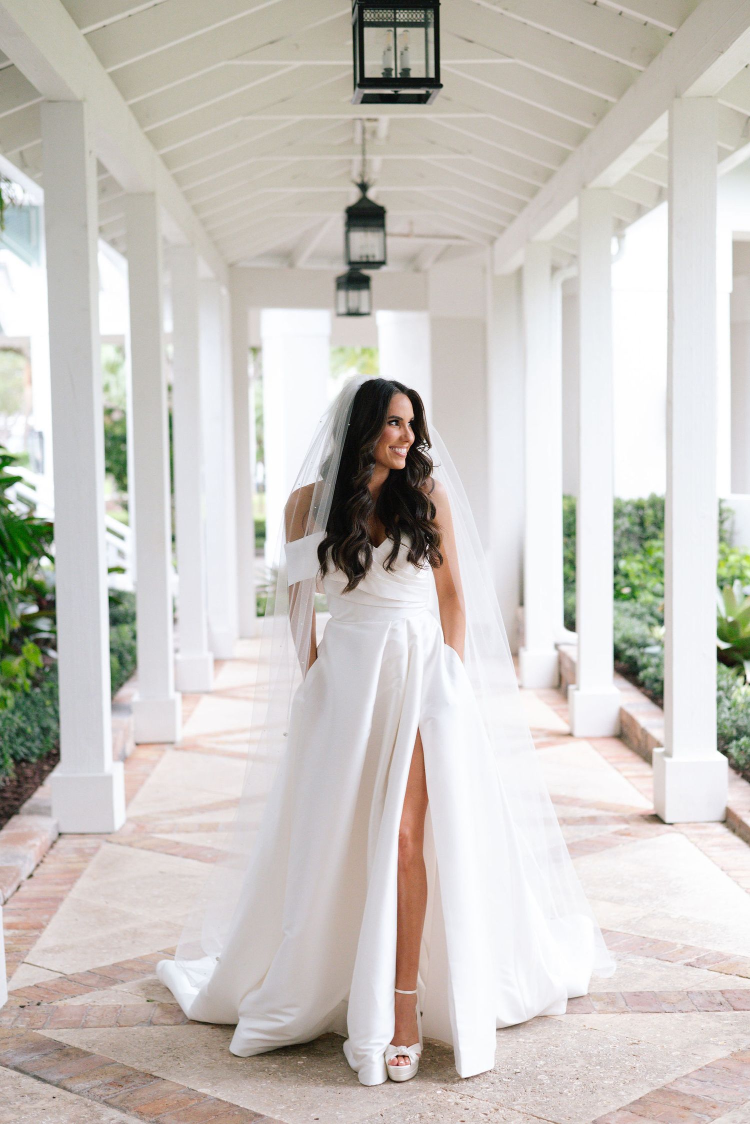 A stunning bridal portrait under a white columned walkway with dramatic lighting.