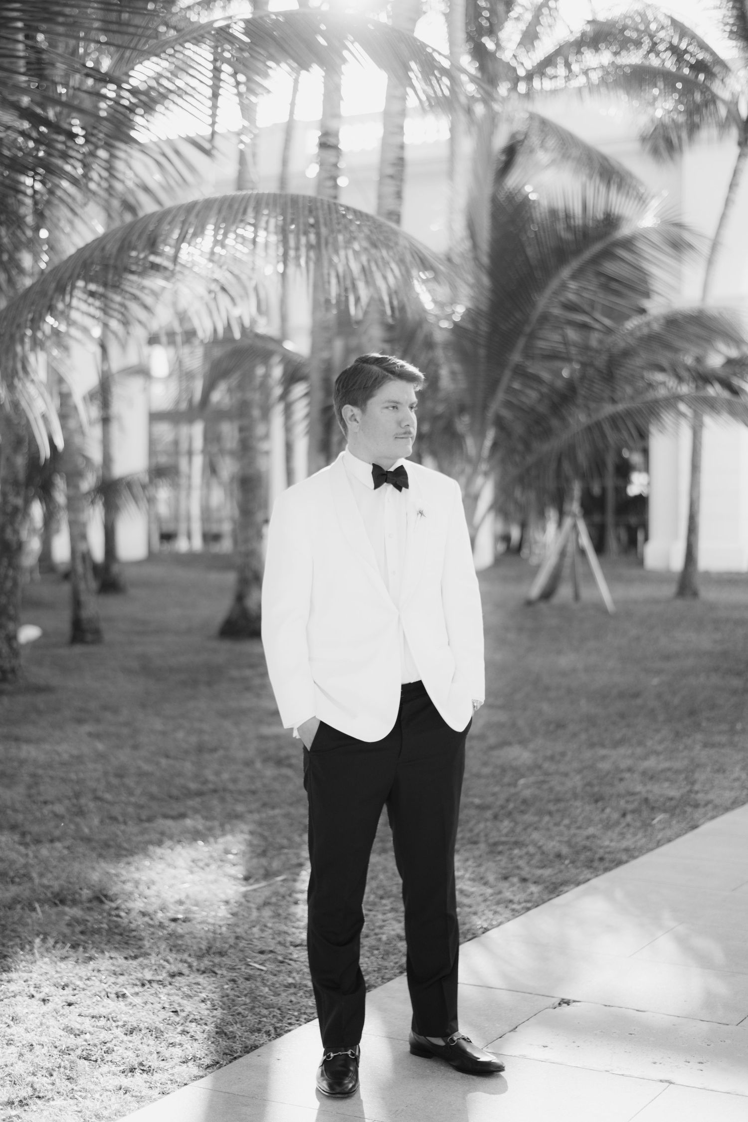 Black and white portrait series showing wedding attire details in a palm-lined venue.