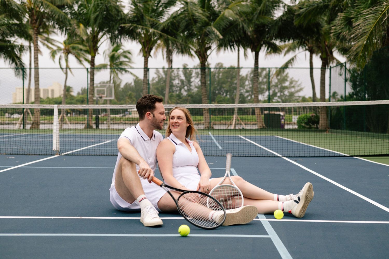 Romantic tennis court photoshoot with palm trees in the background.