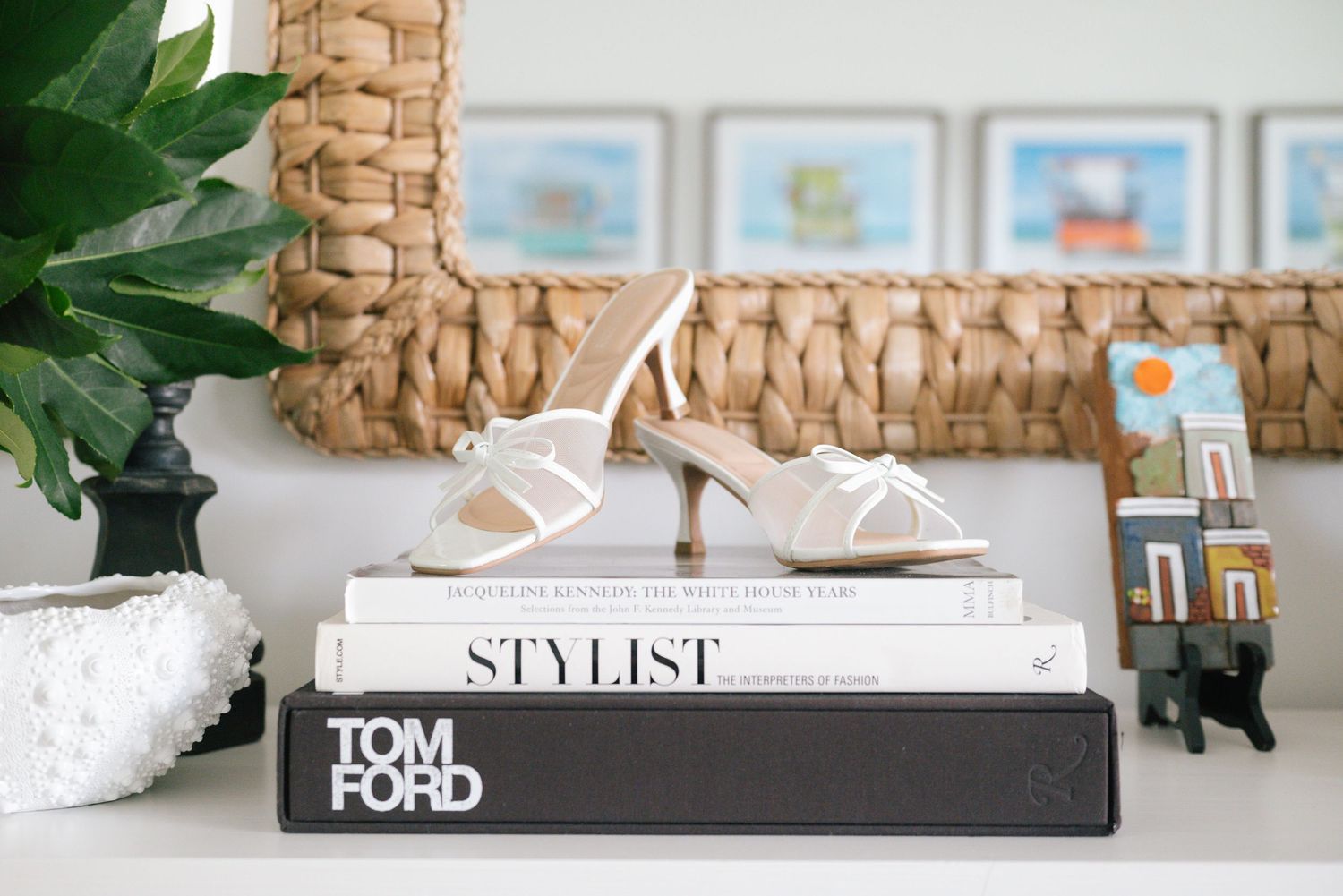A collection of coffee table books and decor items arranged on a white surface with woven basket accents.
