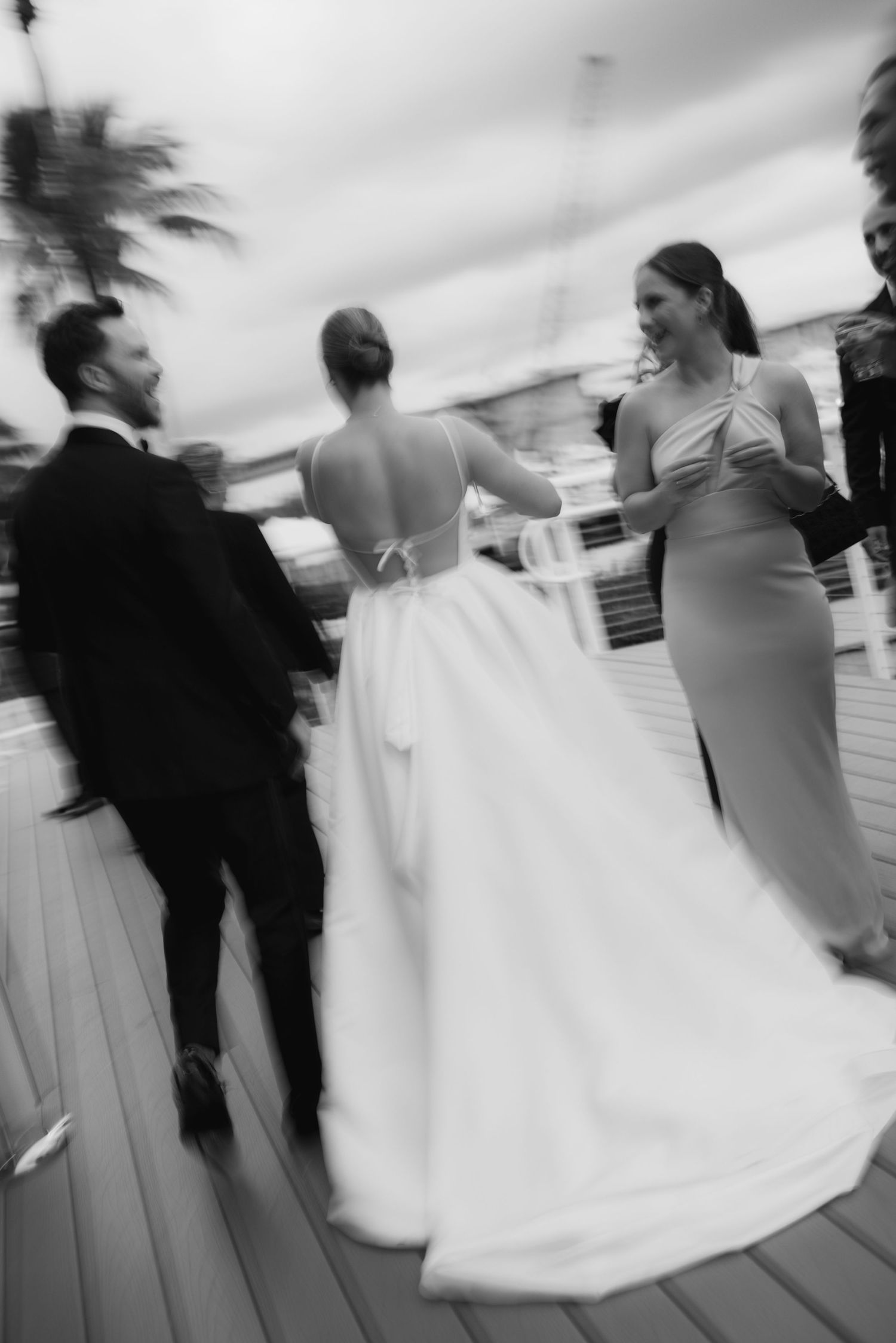 Black and white motion-blurred photos capture couples dancing at a wedding reception on an outdoor deck.