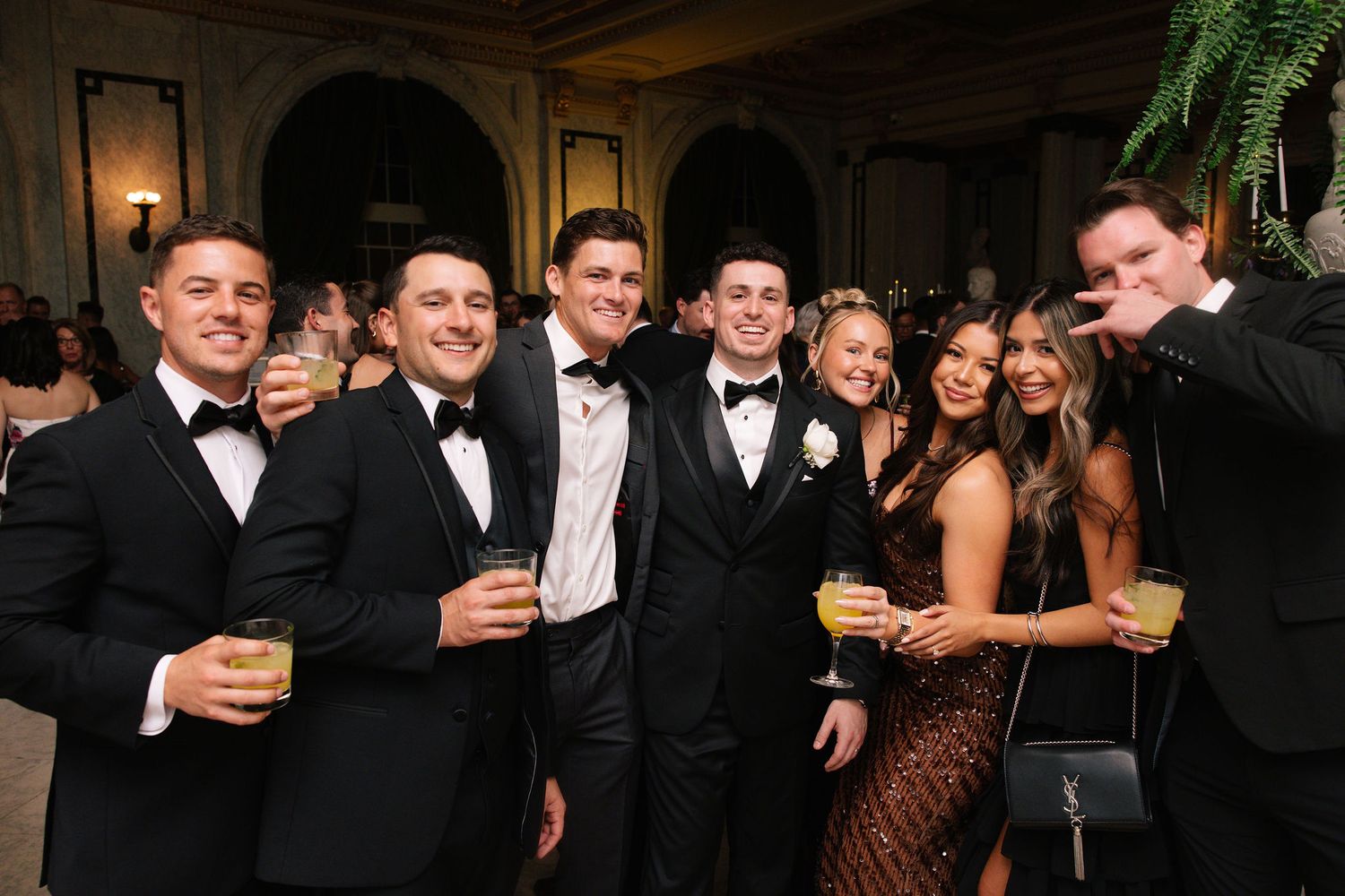 Formal wedding party in black tie attire celebrating at evening reception.