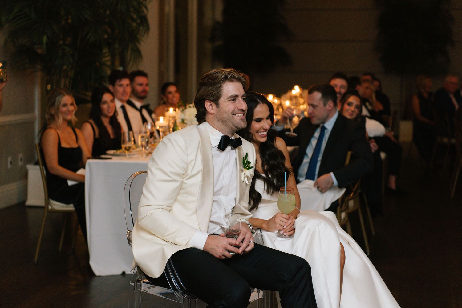 Wedding guests celebrate and applaud during a reception in an elegantly decorated ballroom.