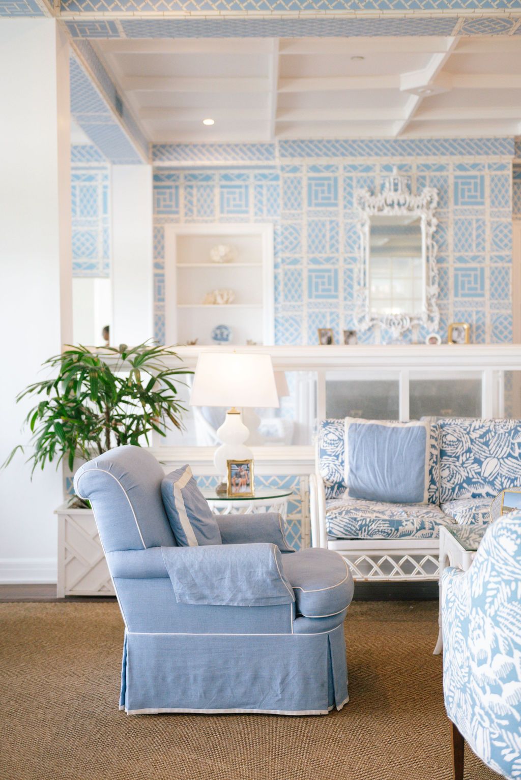 Coastal-inspired sitting room featuring light blue upholstered furniture and geometric wallpaper patterns.