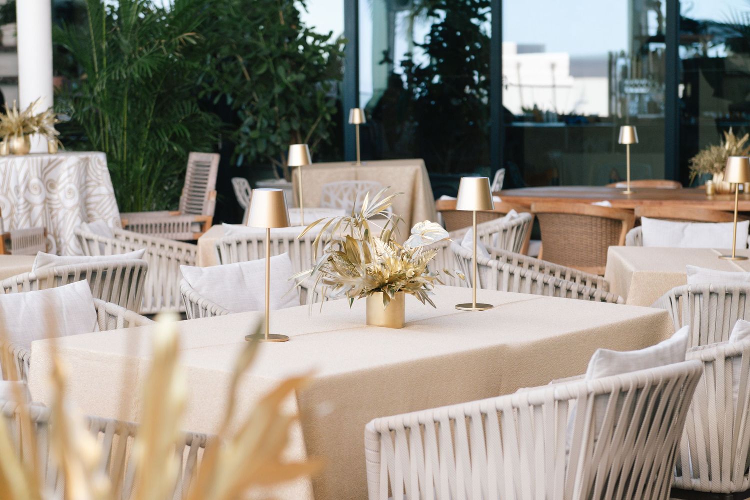 White chiavari chairs and tables with elegant place settings arranged for an upscale wedding reception.