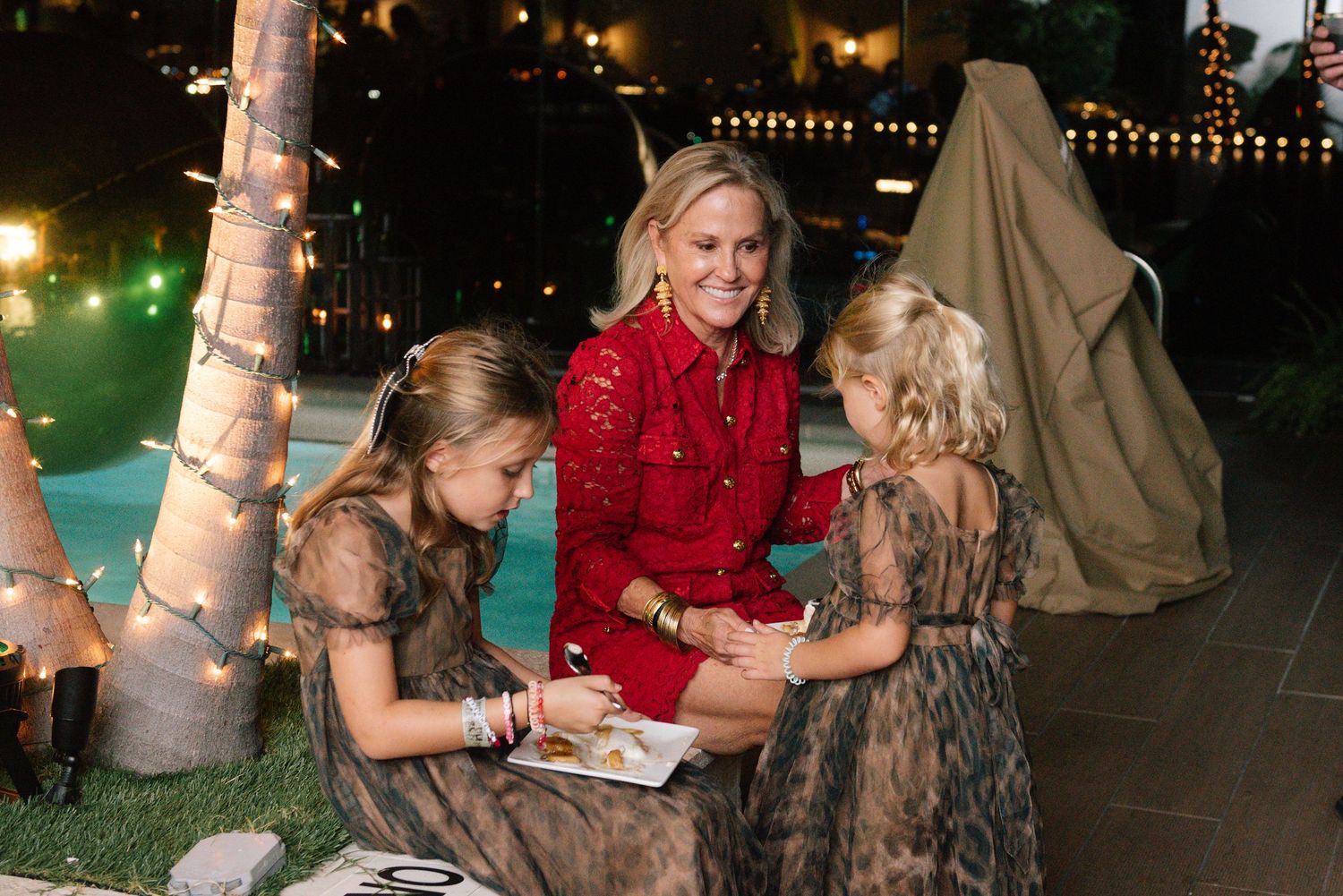 Guests enjoying conversation at an evening outdoor party with string lights.