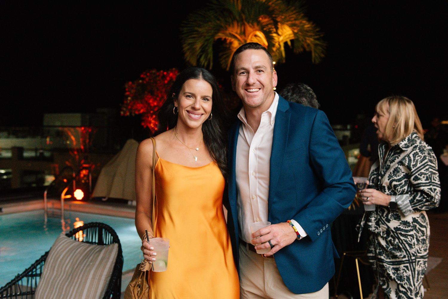 An evening poolside event with palm trees lit up in the background.