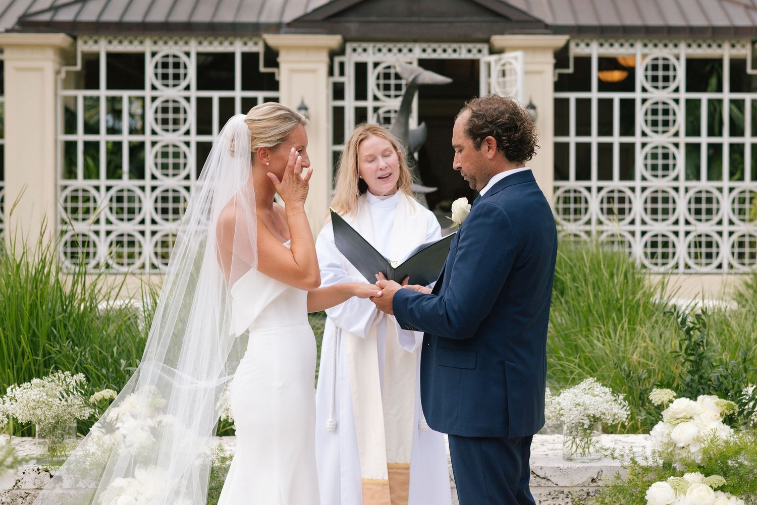 Outdoor wedding ceremony setup with white chairs and decorative architectural details.