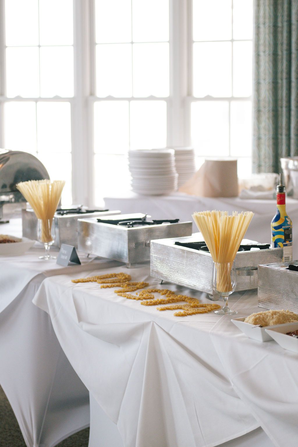White tablecloth buffet setup with pasta and catering supplies in an elegant dining room.
