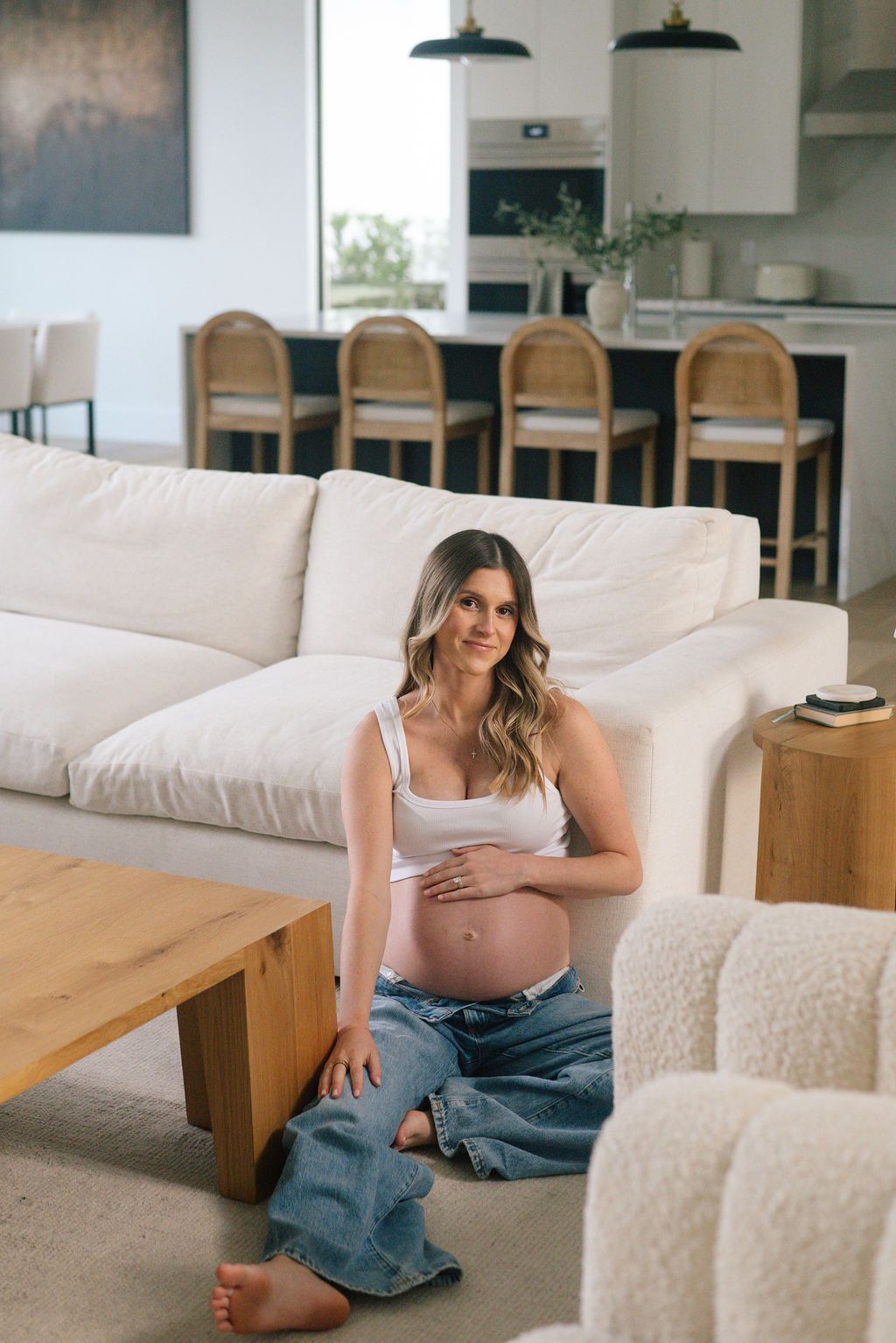Maternity session in bright modern living room with white furniture.
