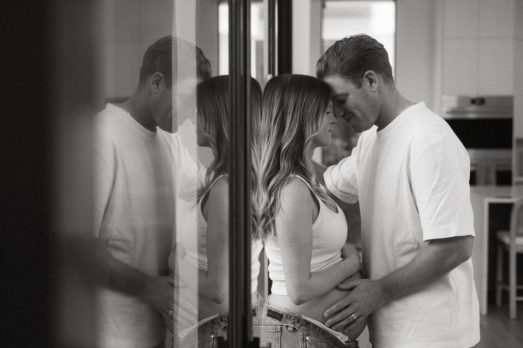 Romantic couple embracing in front of window in contemporary home setting.