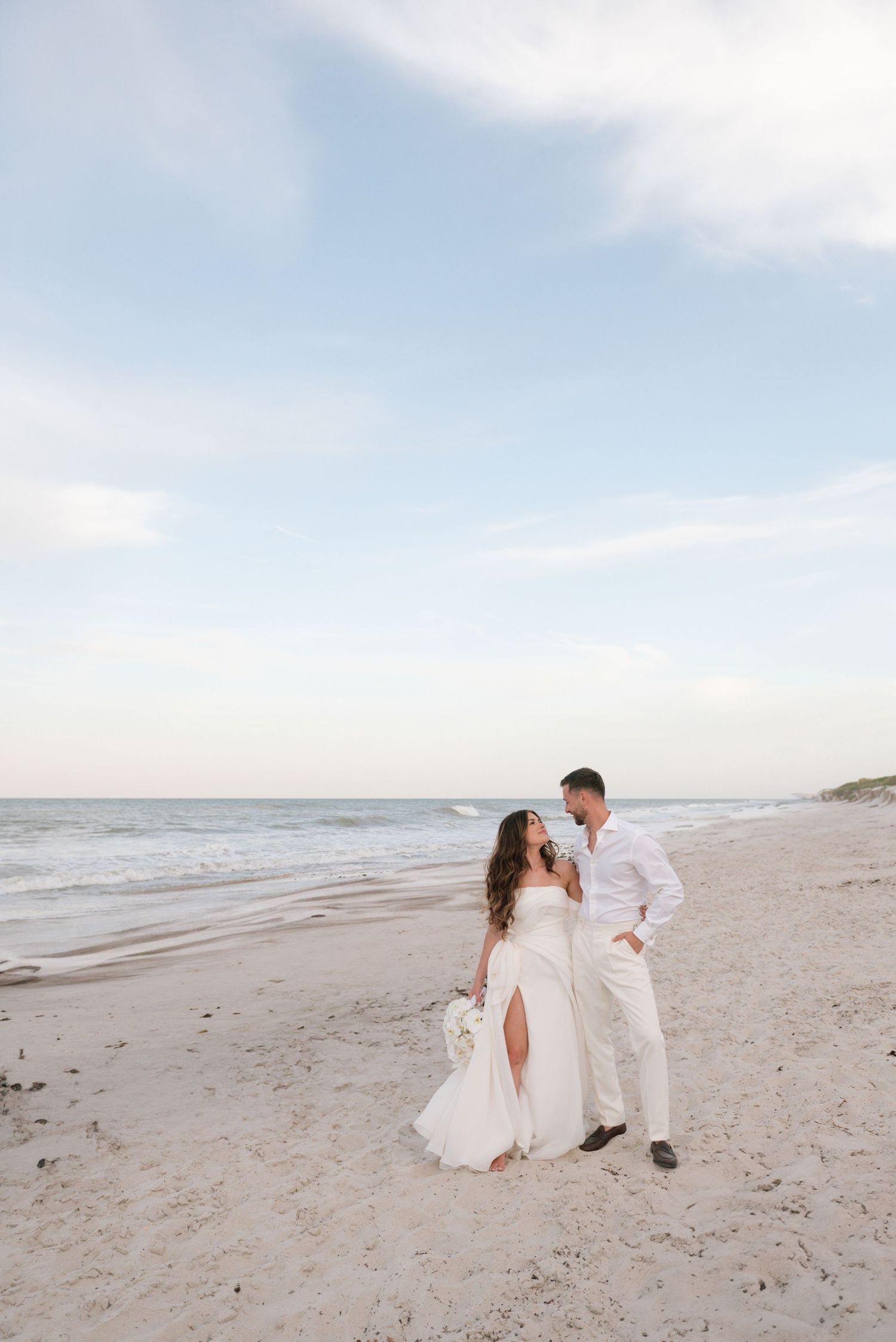 A dreamy beach wedding photo with the ocean and sky creating a serene backdrop.