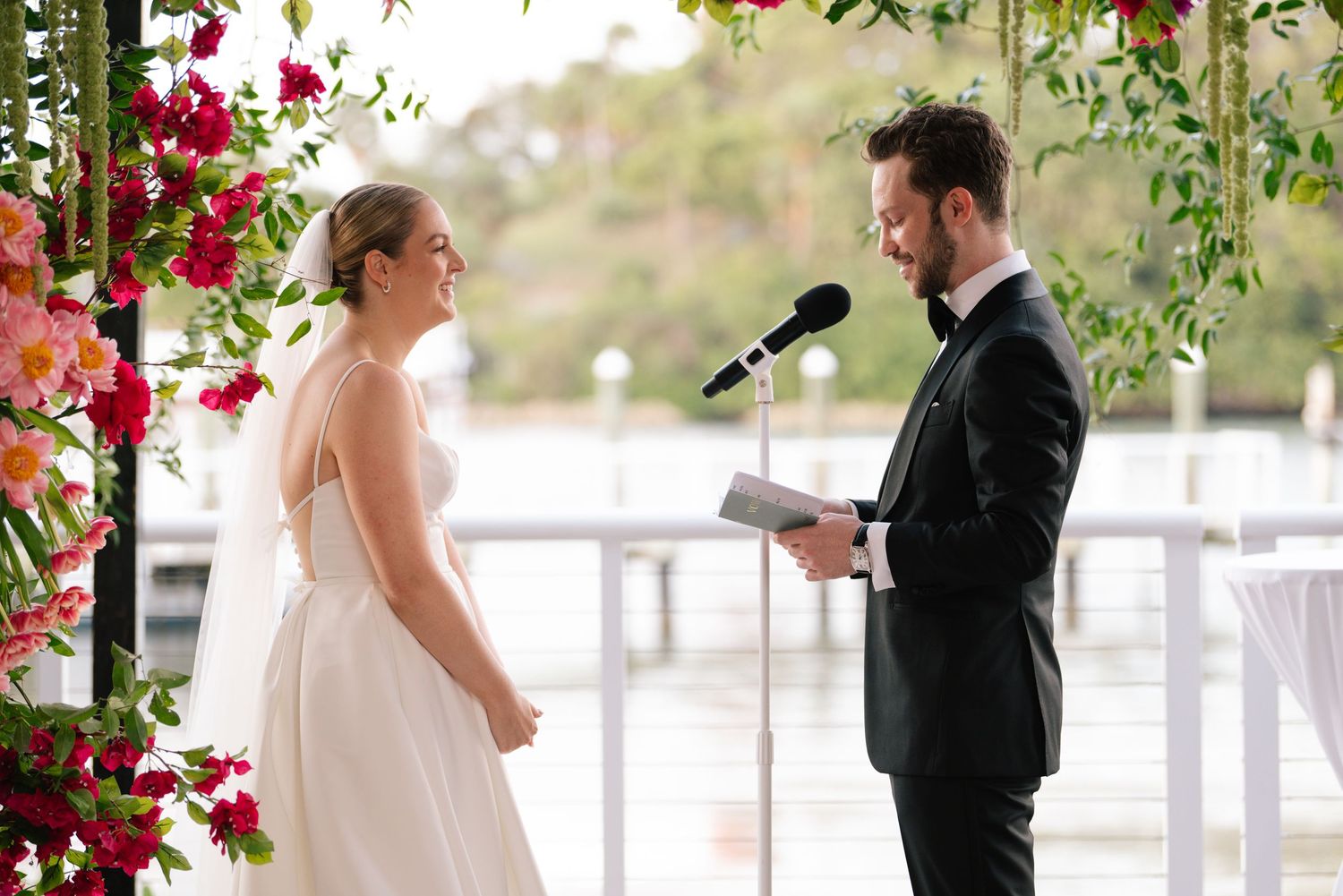 Couple shares intimate moment during wedding ceremony beneath floral arch.