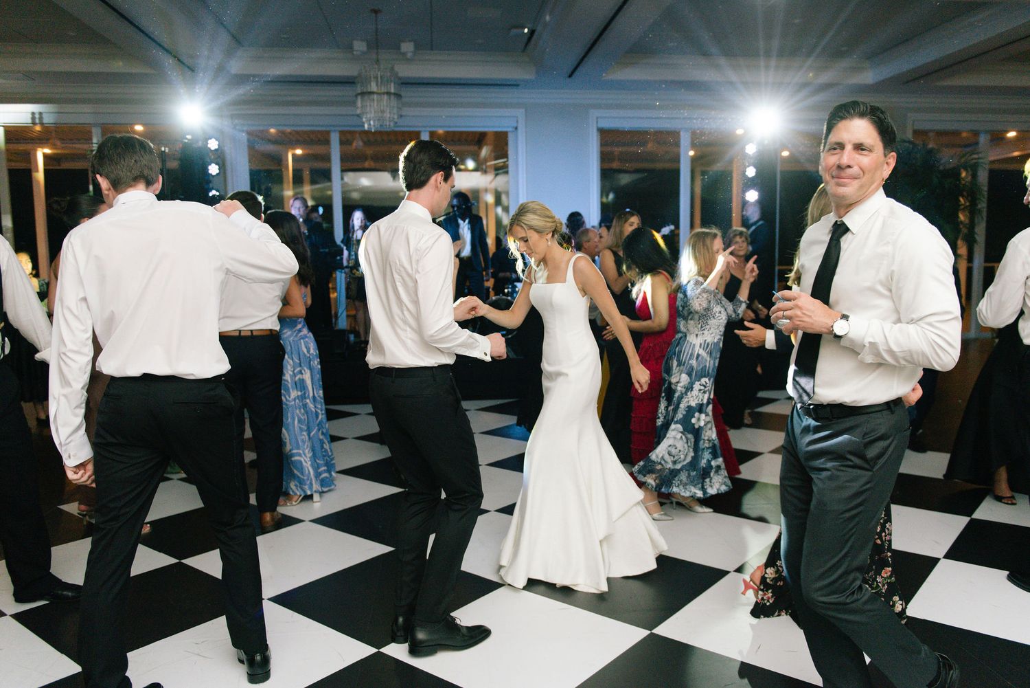 Guests enjoying a wedding reception dance party on a striking black and white checkered floor.