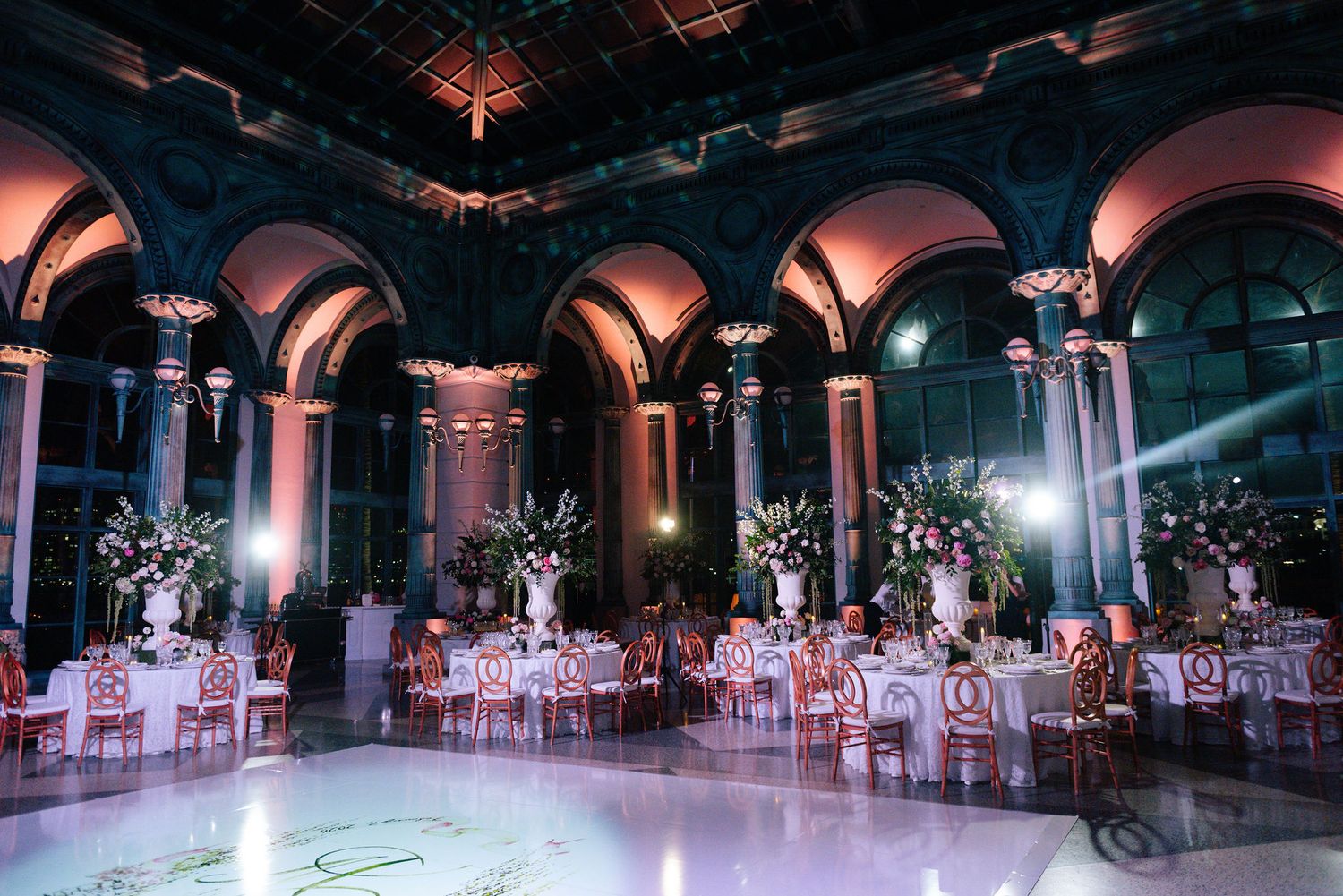 Panoramic view of a luxurious ballroom decorated with flowers and elegant table settings.
