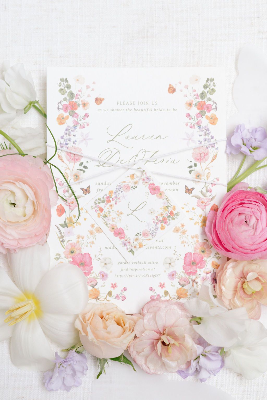 A delicate wedding invitation featuring watercolor floral designs surrounded by fresh flowers.