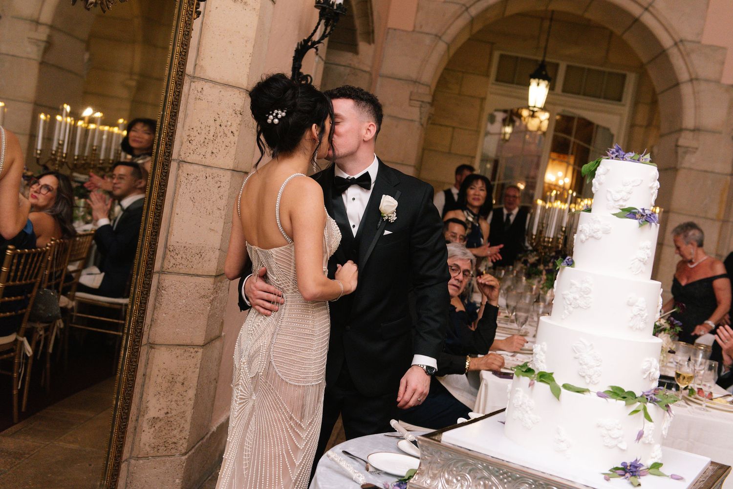 Wedding celebration in a grand ballroom with stone archways and decorative lighting.